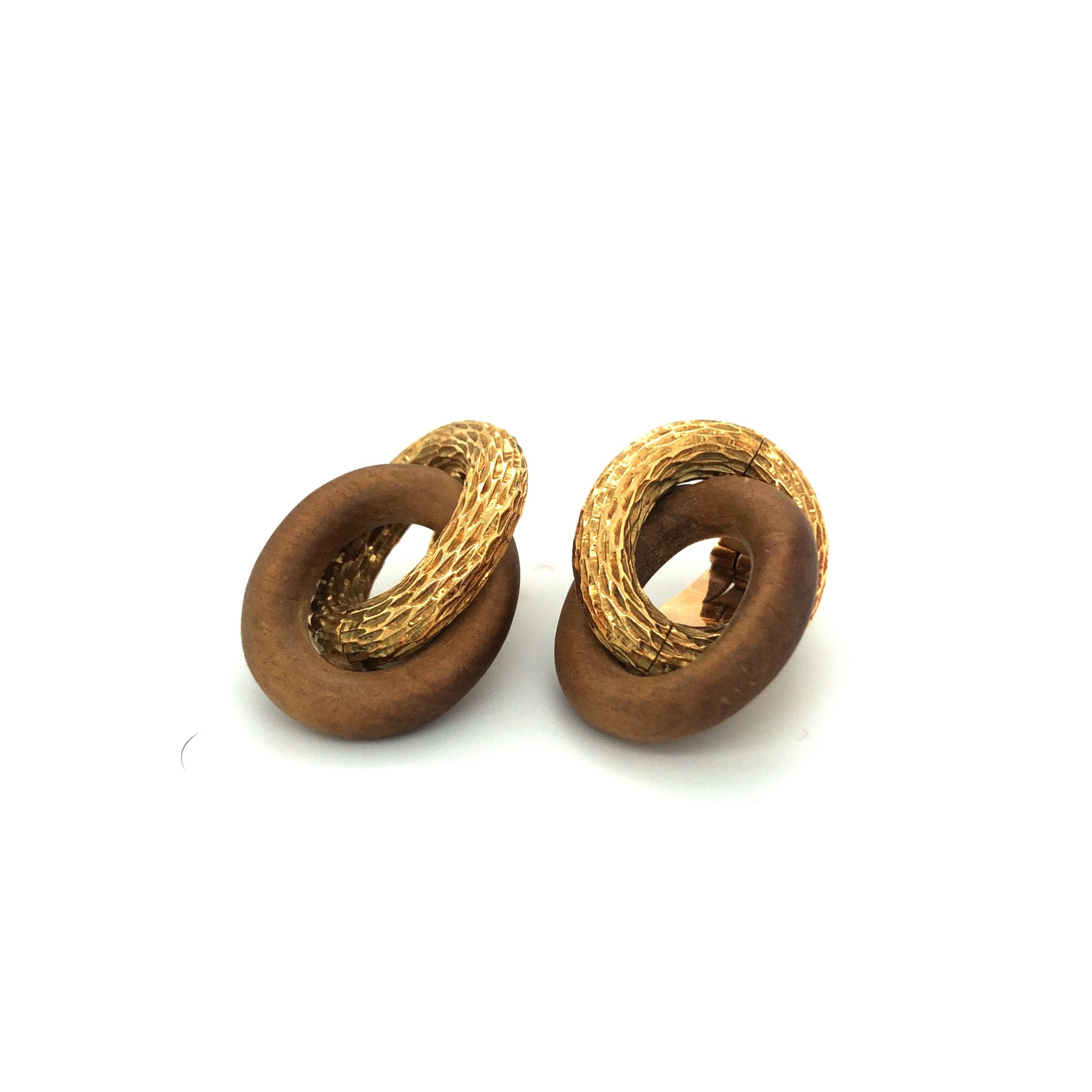 Pair of 18 karat yellow gold and sandalwood vintage ear clips by René Boivin, each composed of two interlocking oval rings - one in structured yellow gold imitating wood and the other one in polished sandalwood. 
These ear clips were crafted in the