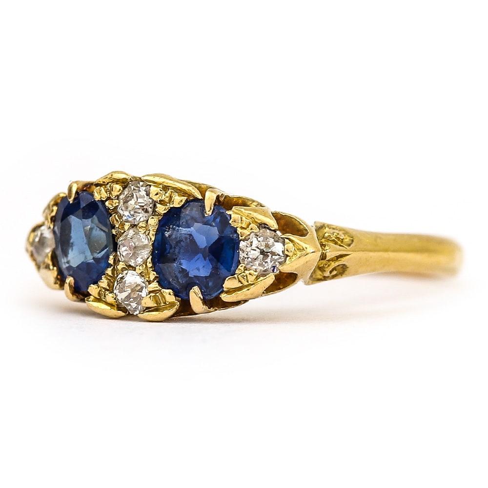 An 18 karat yellow gold Victorian boat shaped ring set with two round sapphires each est. 0.35cts making a total sapphire weight of 0.70cts. Five eight cut diamonds est. 0.15cts are millegrain set in the head of the ring, making this design typical