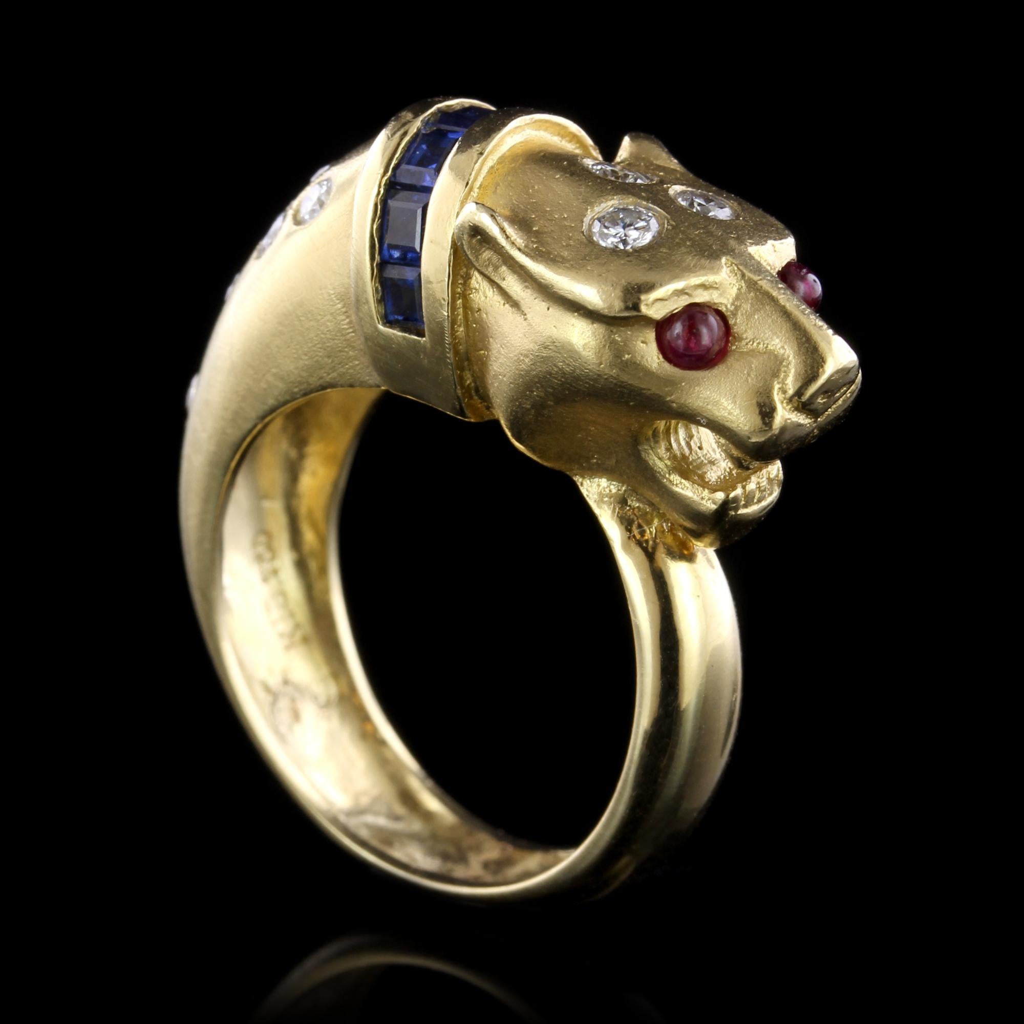 18K Yellow Gold Sapphire, Ruby and Diamond Lion Head Ring. The ring is set with seven square cut sapphires approx. total wt. .40cts., further set with 12 full cut diamonds approx. total wt. .33cts., HI color, SI clarity, and two cabochon ruby eyes,