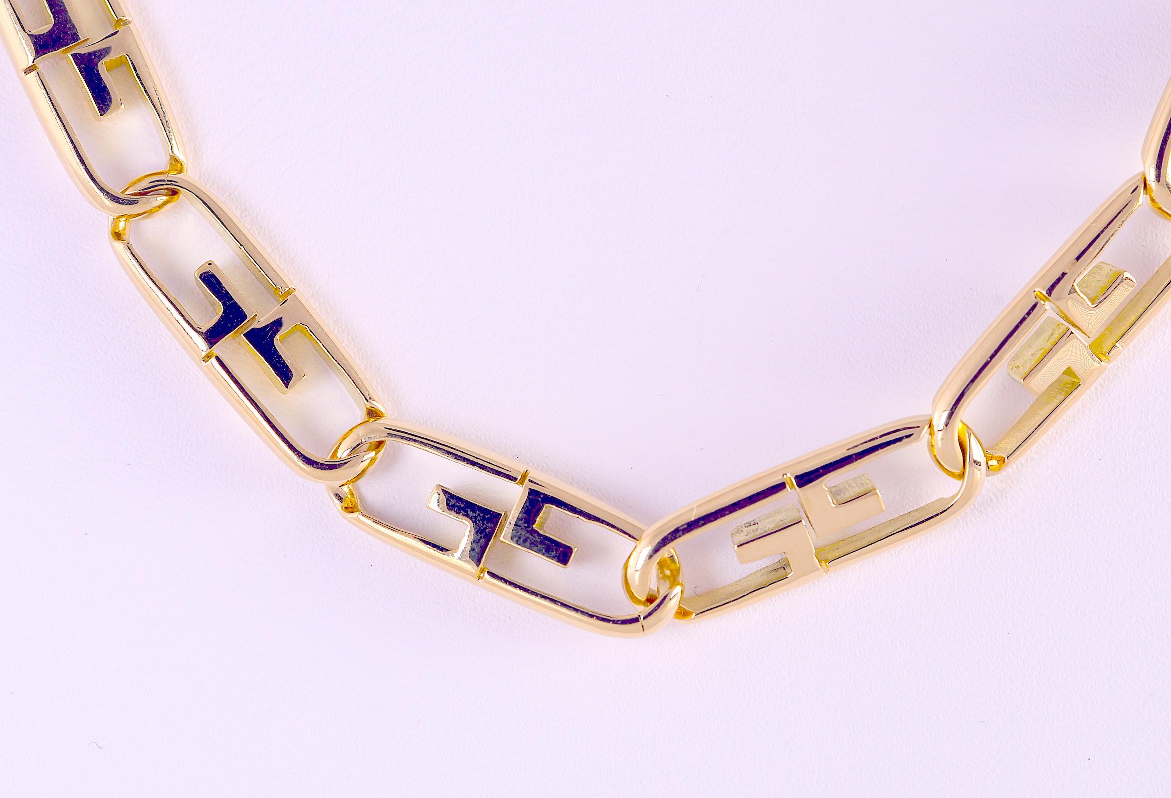 An elongated oval link with geometric center bar 18 karat yellow gold necklace. The necklace measures 28 inches long and 5/16 inch wide. The closure is a lobster claw clasp. The necklace weighs 91.0 grams. The necklace is stamped and professionally