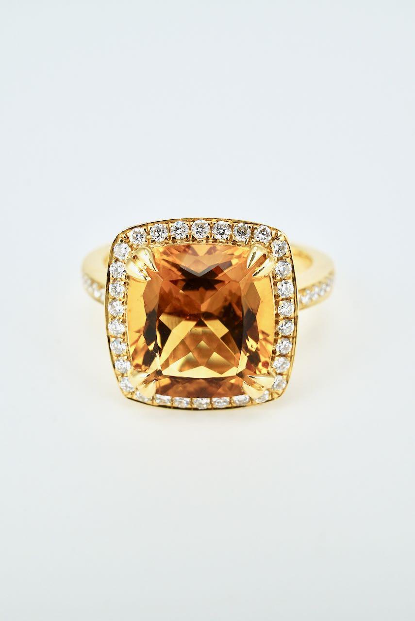 A dress ring featuring a cushion cut citrine of good rich toffee colour four split claw set within a border of 30 round brilliant cut diamonds and with a further 14 round brilliant cut diamonds to the shoulders on a square profile shank - a smart