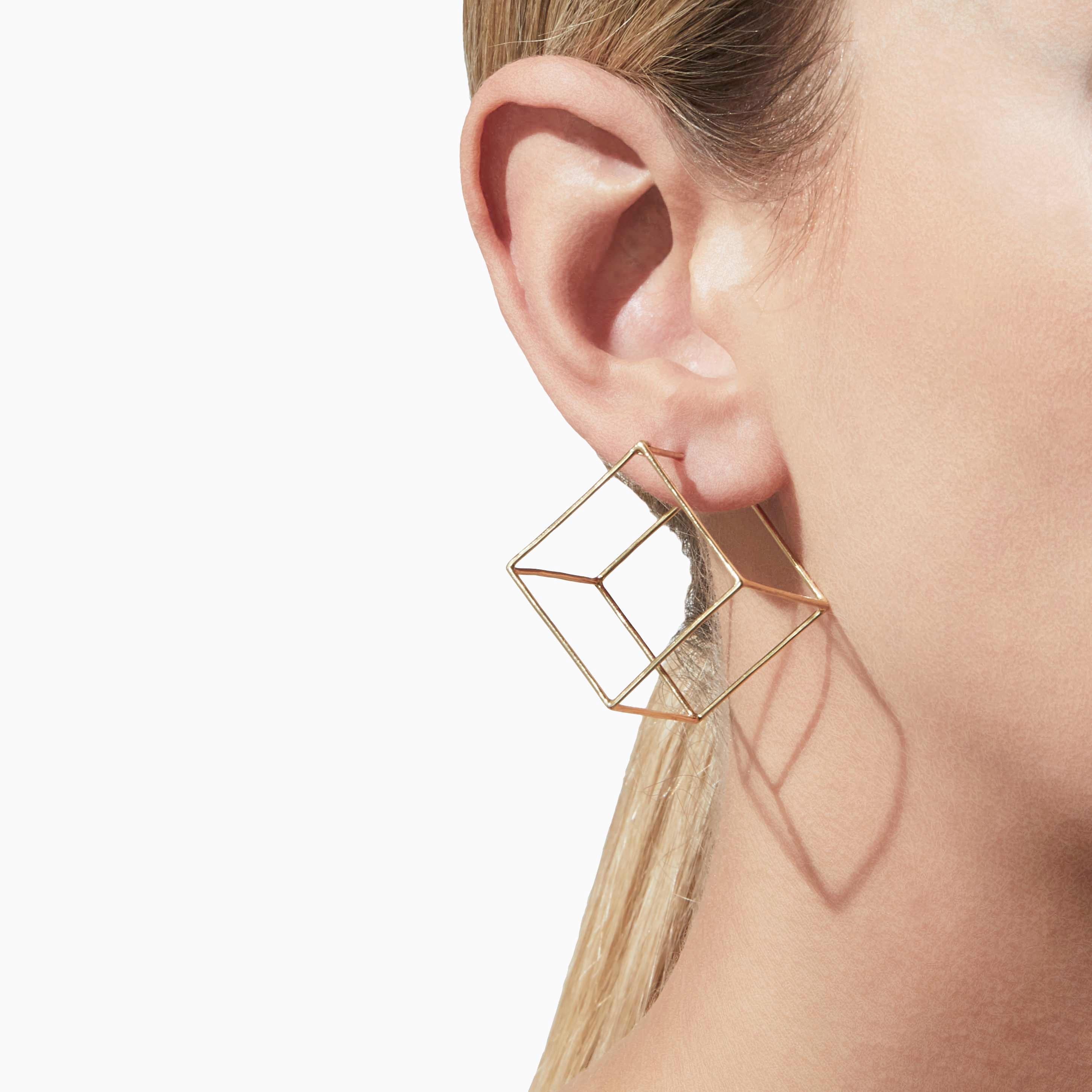 The three dimensional cubic form appears to float seamlessly around the earlobe when worn. One side is an earring post. You can alter the point at which the earring hangs depending on how you want it to appear. 

18 Karat Yellow Gold Square Pair