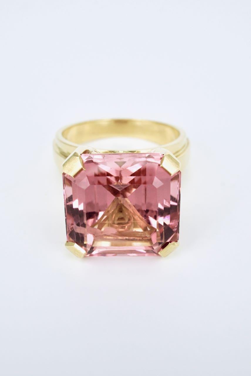 A dress ring featuring a square emerald cut pink tourmaline of approx 15cts of medium pink colour and very good clarity four claw set in 18k yellow gold above a tapered shank - a beautifully cut tourmaline stone of soft pink colour in a classic