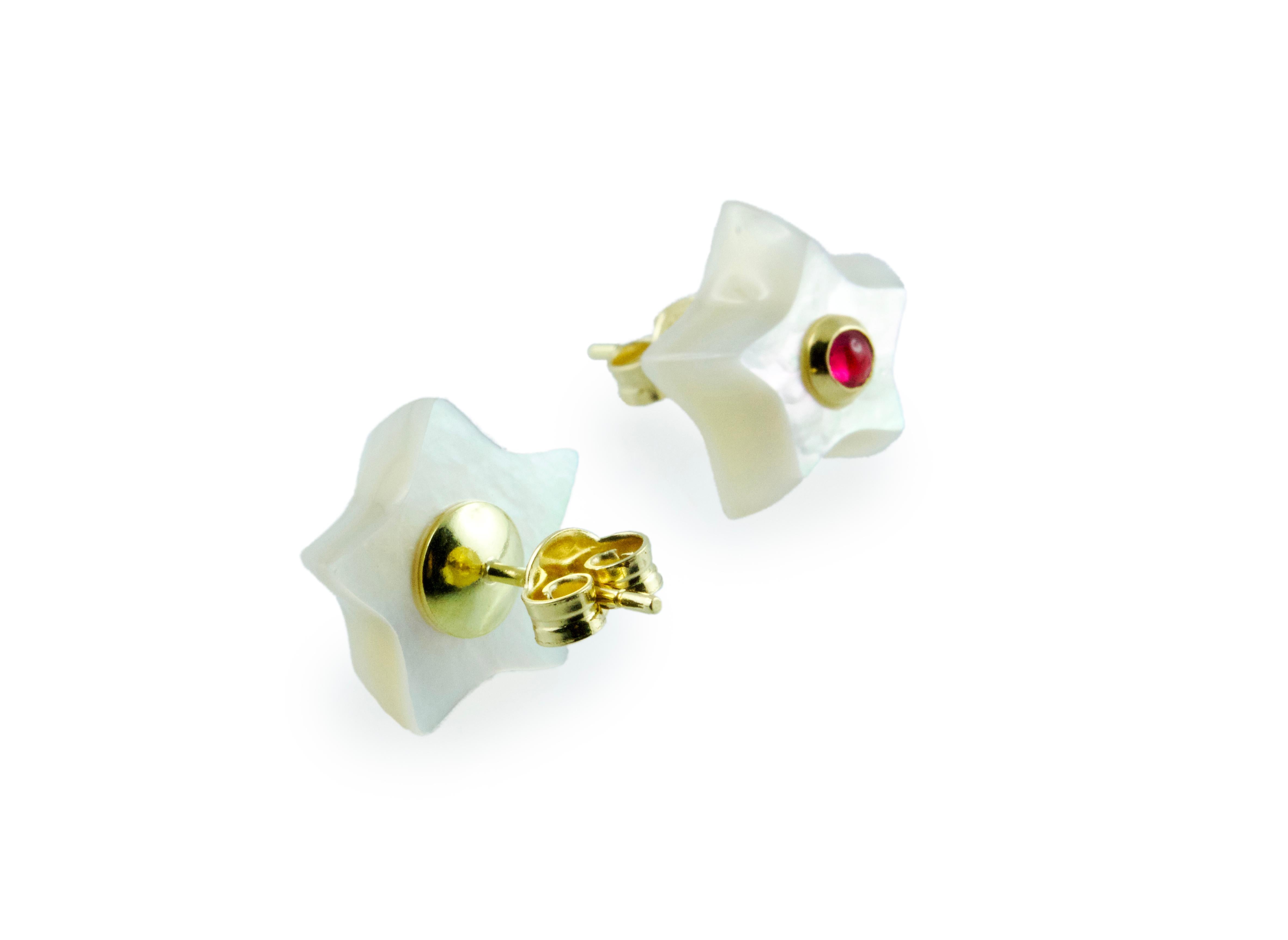 This charming pair of stud earrings is entirely made in mother of pearl, shaped as stars and adorned in the center with cabochon rubies. 
The routing is in 18k yellow gold. 