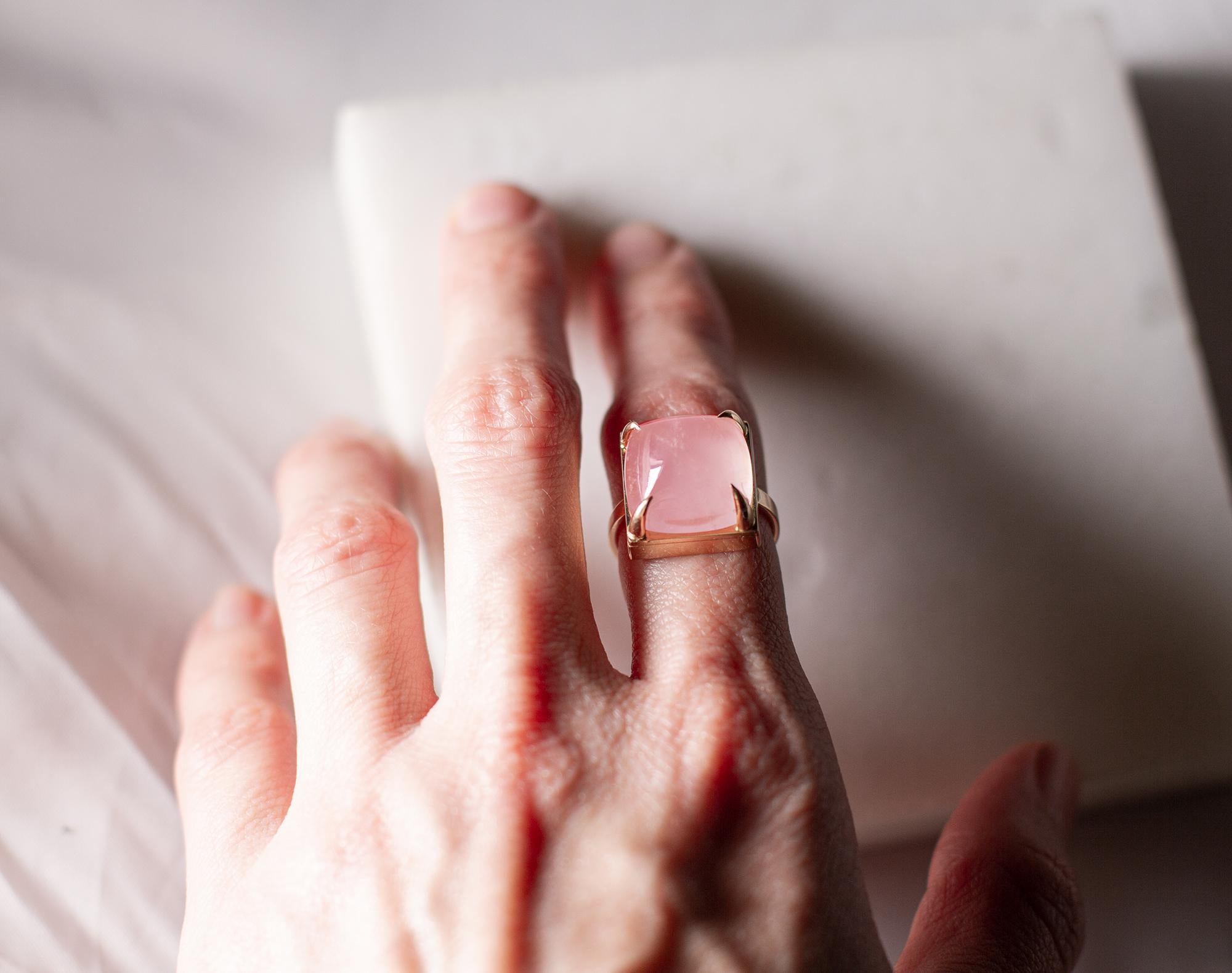 This ring is made of 18 karat yellow gold with a sugarloaf cut natural light pink quartz.

Typically, the smaller the prongs, the better for most gems. However, we wanted to avoid the typical childish look that often occurs with sugarloaf gems that