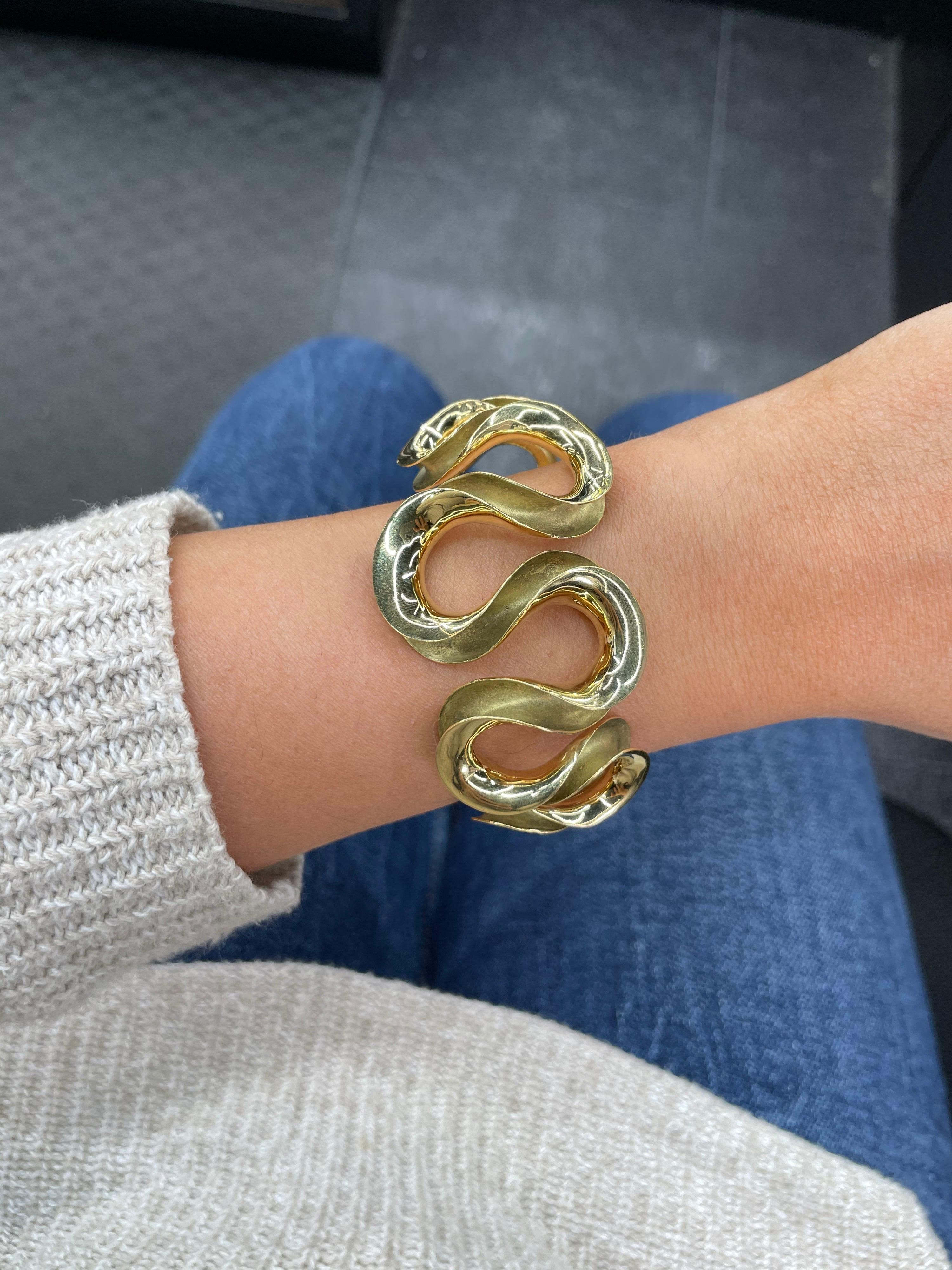 18 Karat yellow gold bangle cuff featuring a swirl motif weighing 47.6 grams. 