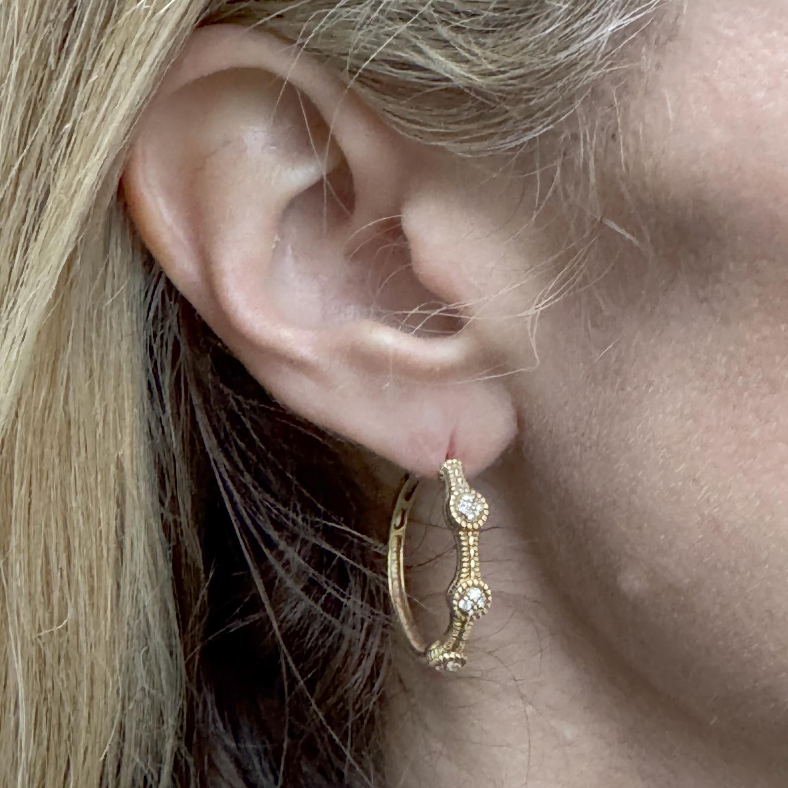 Ces boucles d'oreilles modernes en or jaune 18 carats présentent une finition joliment texturée, ajoutant profondeur et dimension à leur design élégant de 1 pouce. Chaque anneau est orné de trois stations de diamants, mettant en valeur un total de