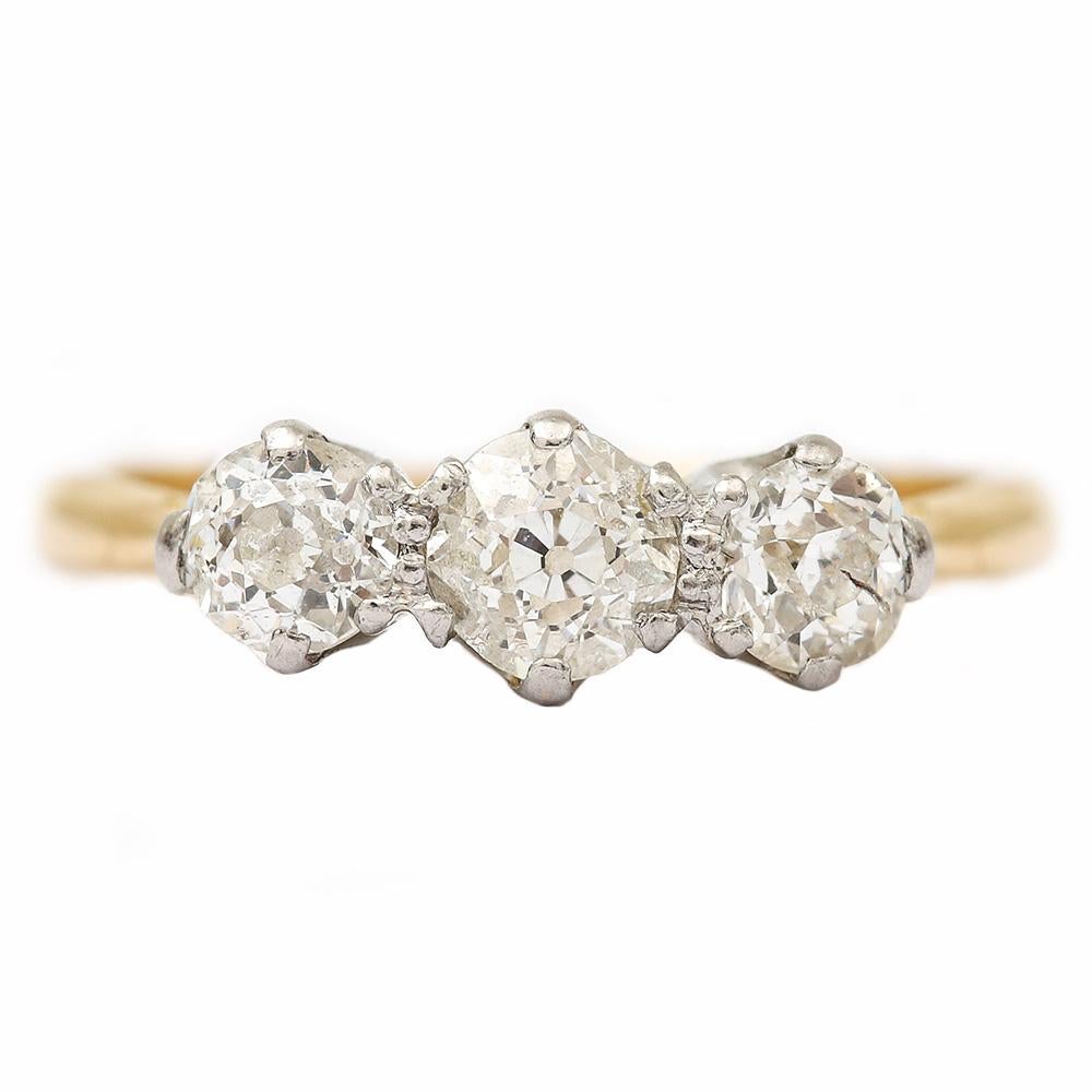 A pretty antique 18 karat three stone diamond ring set in platinum dating from the early 20th Century. The three diamonds are all Old Mine cut stones a precursor to the modern brilliant cut diamond, another indicator that this is an older ring. The