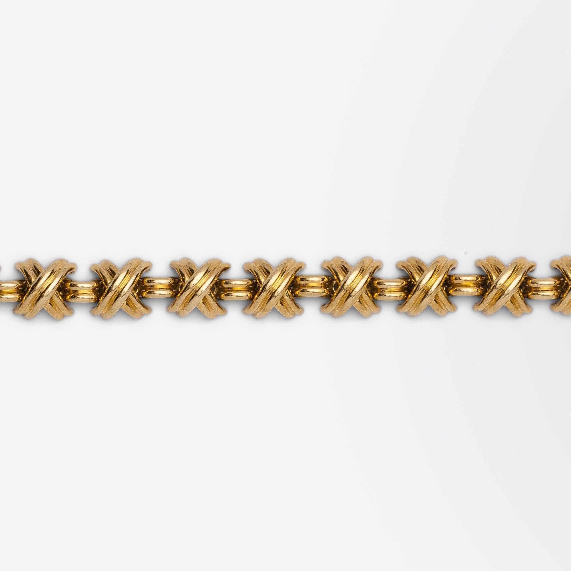 A beautifully heavy and iconic piece of armwear by Tiffany & Company known as the 'Signature X' bracelet. The solid 18 karat gold bracelet consists of groved domed 'X' shaped links with a curved small bar link between each. The hefty bracelet is