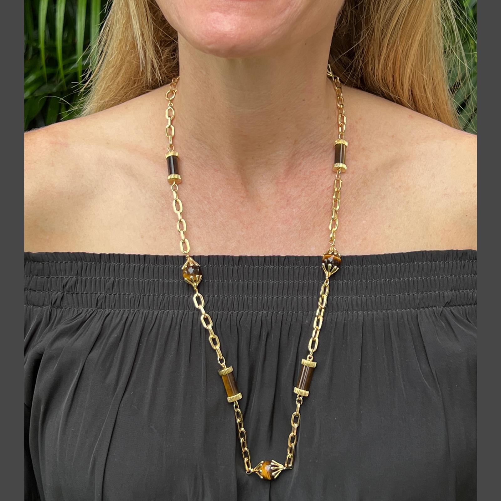 Long link necklace featuring tiger's eye gemstones and 18 karat yellow gold. The 27 inch necklace features 4 round tiger's eye stations and 5 tubular tiger's eye stations. 