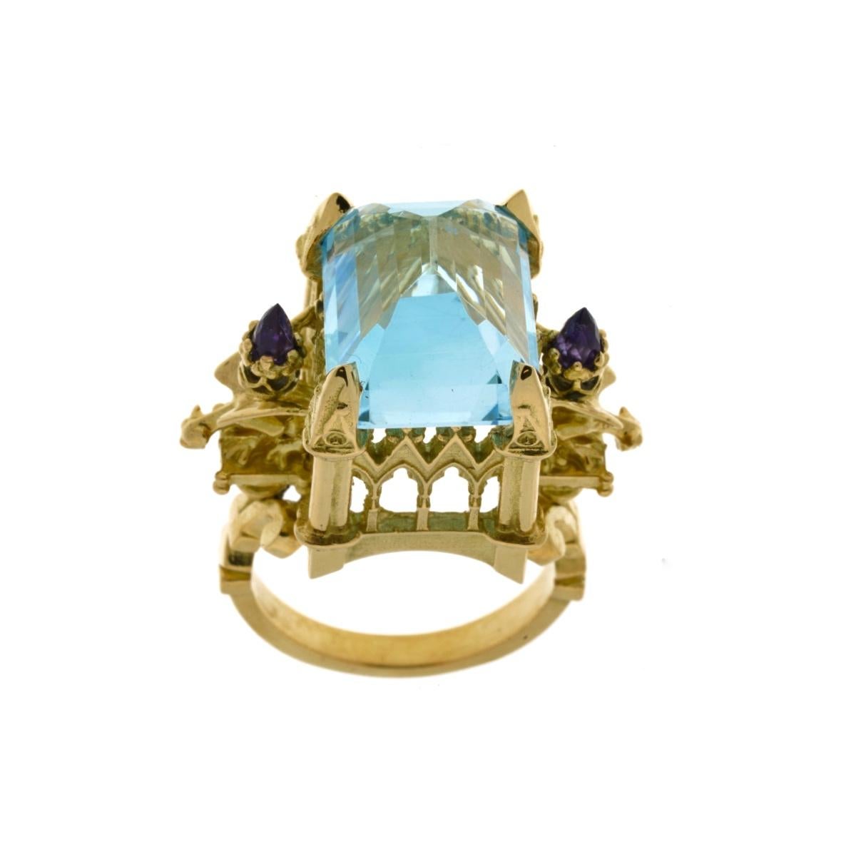 La Gargouille Cathedral Ring is a truly wondrous one of a kind piece.

Handcrafted in 18kt yellow gold this glorious ring features a stunning central 15mm x 12mm crisp blue topaz, resplendent atop a signature William Llewellyn Griffiths cathedral