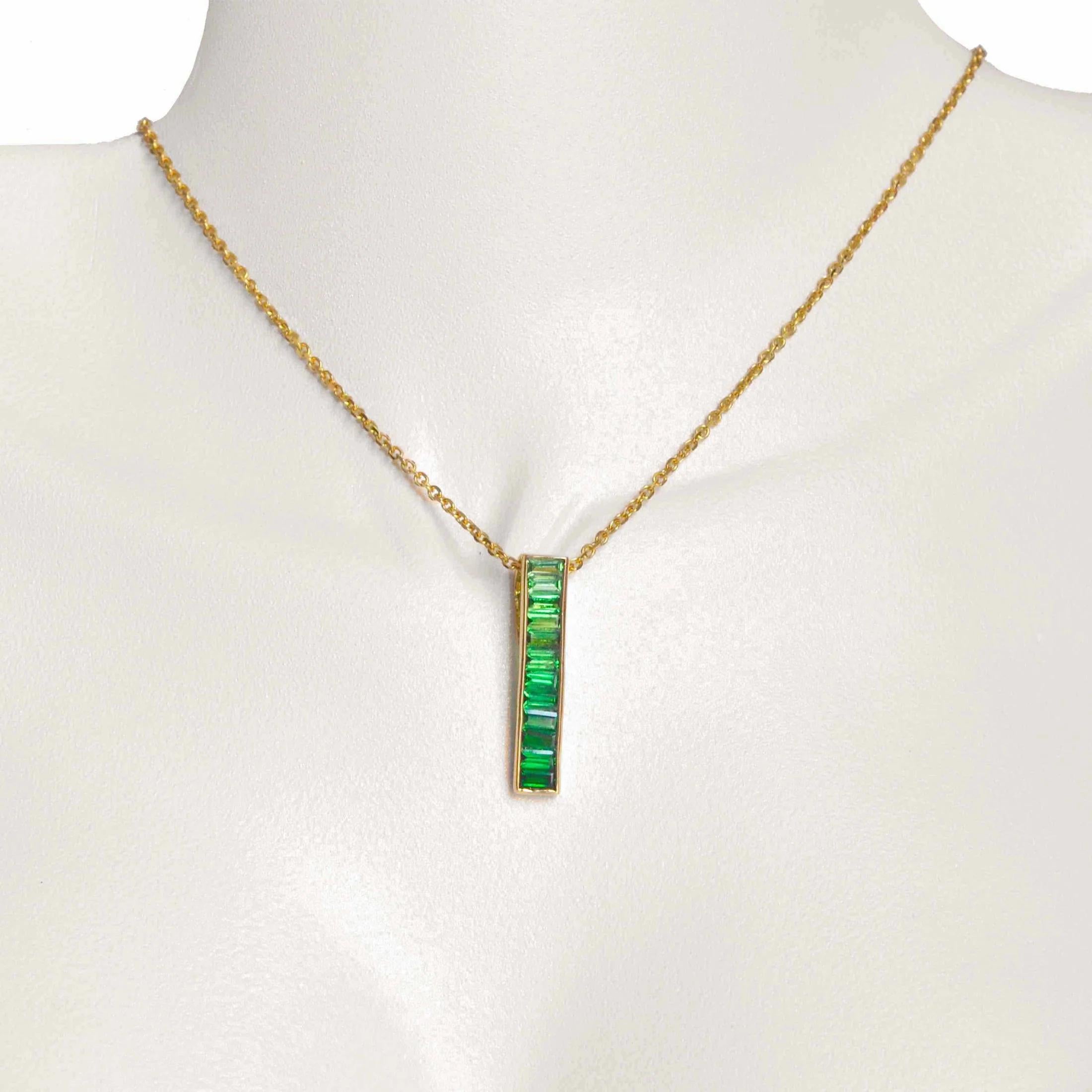 Adorn yourself with the exquisite allure of the 18K Gold Tsavorite Baguette Bar Pendant, a graceful fusion of nature's beauty and contemporary elegance. This pendant showcases a sleek bar design, meticulously embellished with vibrant green tsavorite