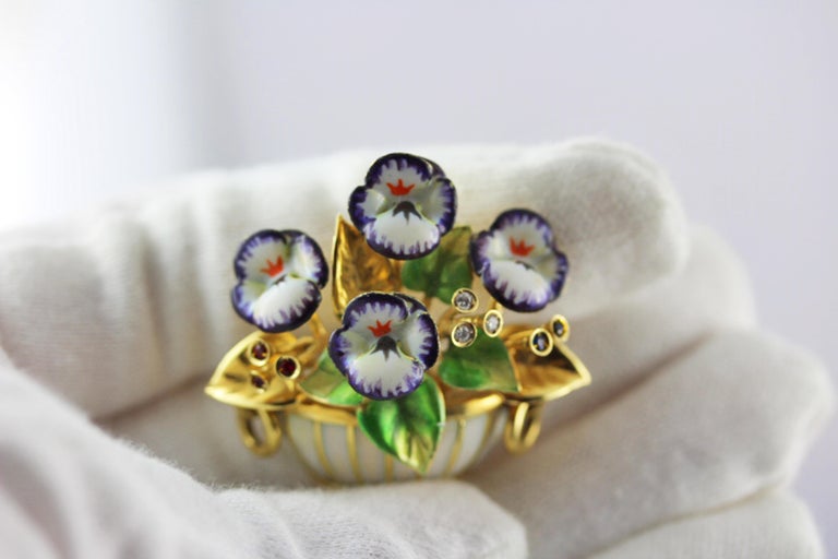 Amazing polychrome enamel violet floral bouquet brooch made in 18 karat yellow gold.
This brooch is modeled as a bouquet of four violets put on a pot whited enameled, each flower is decorated with purple, white and orange enamel petals, all the
