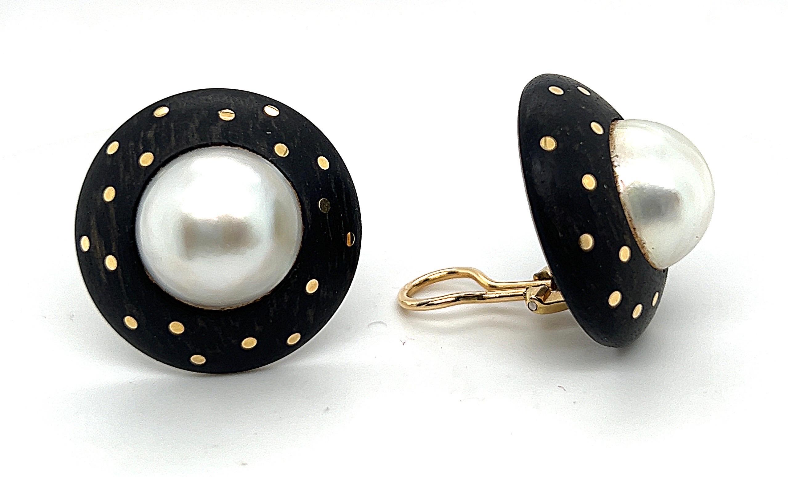 Eye-catching pair of 18 karat yellow gold, wood and mabe pearl earrings by Swiss jeweler Devon.
Large round earclips each consisting of a dark wood disc, centering upon a mabe pearl of circa 15.2 mm ( 0.6 in ). The wood is decorated with tiny gold