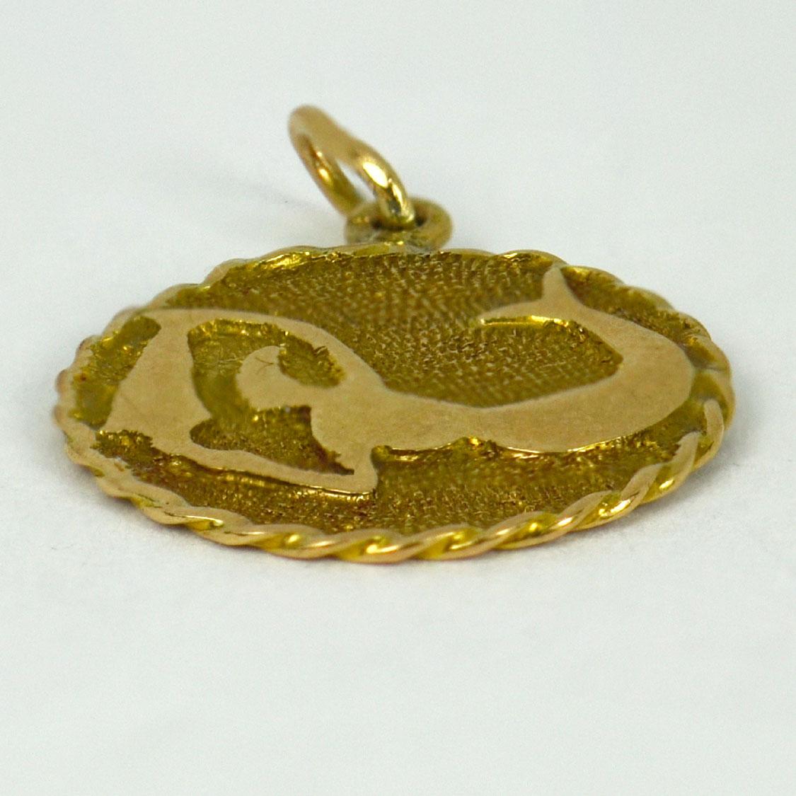 An 18 karat (18K) yellow gold charm pendant designed as a disc depicting a mermaid with a water jug to represent the Zodiac sign of Aquarius. Stamped with the owl mark for French import and 18 karat gold, engraved to the reverse
