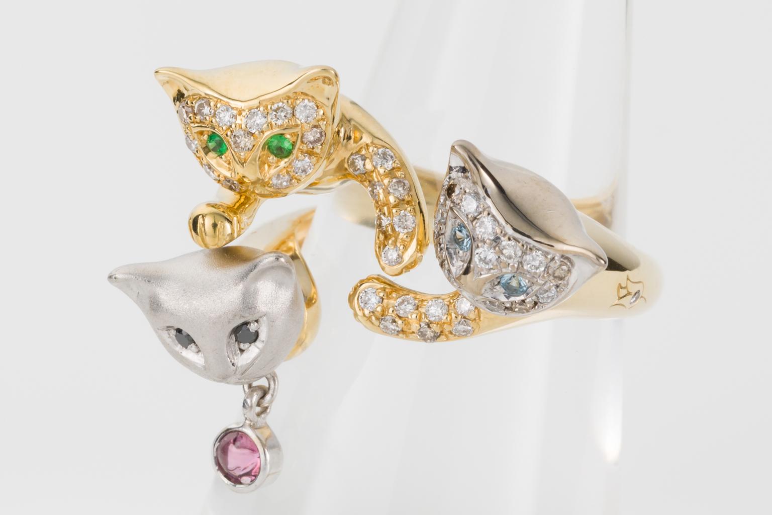 How cute is this ring? Purrrfect for a cat lover and definitely a talking point when people see this unique style.
Designed as three cats looking up, one in yellow gold with pave set diamonds and green emerald eyes,  the next is brushed 18k white