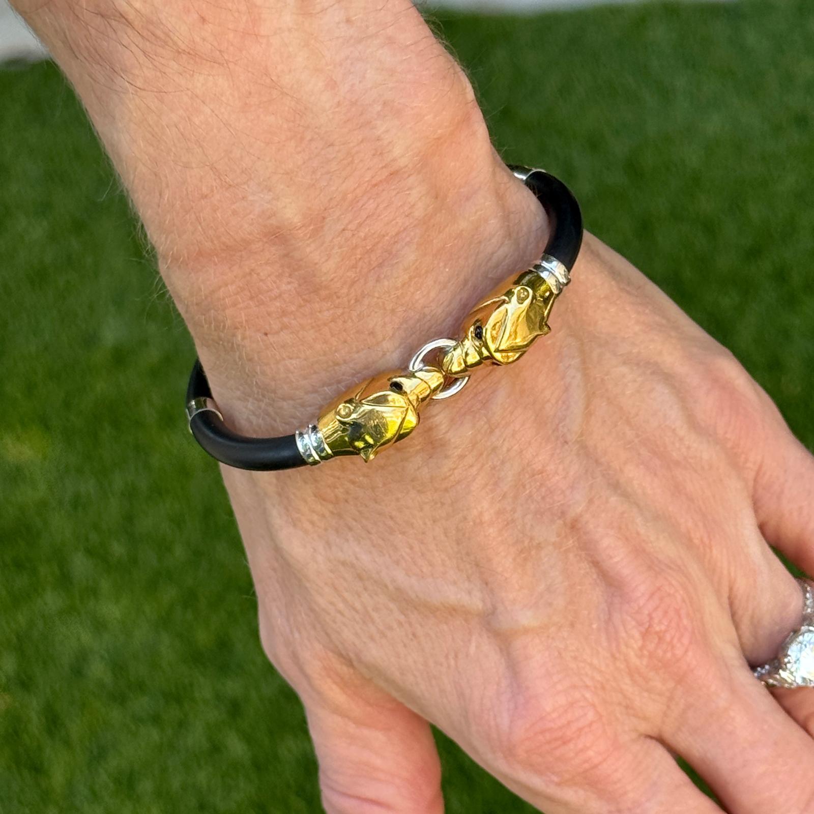 Ce bracelet frappant présente deux têtes de panthère en or jaune et blanc 18 carats, reliées par un élégant élastique noir pour un look moderne et audacieux. L'association de l'or luxueux et du caoutchouc durable crée un contraste dynamique, mêlant