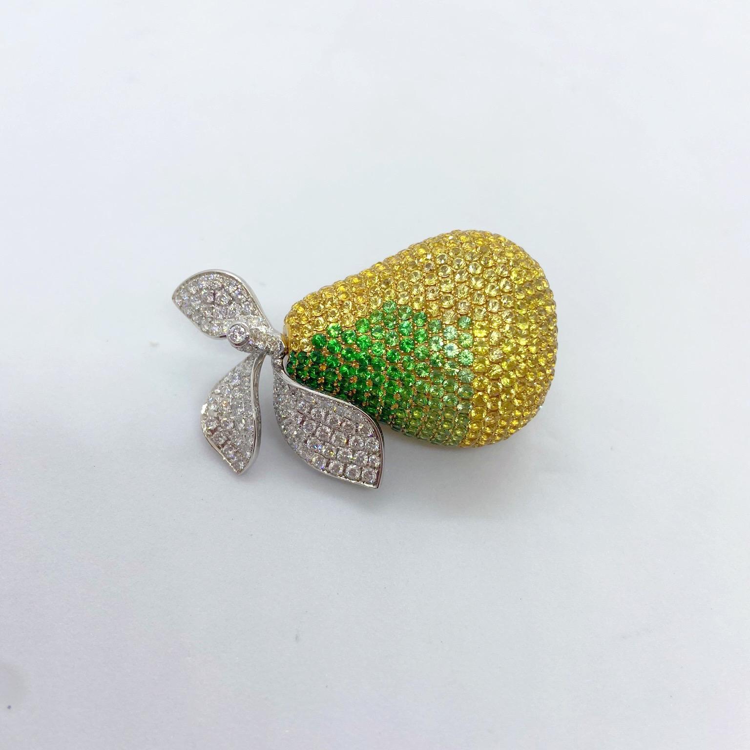 An 18 karat yellow and white gold multi dimensional pear brooch. The yellow gold pear is meticulously set with round Yellow Sapphires and an ombre of round Green Tsavorites. The white gold leaves are set with round brilliant Diamonds. The pear