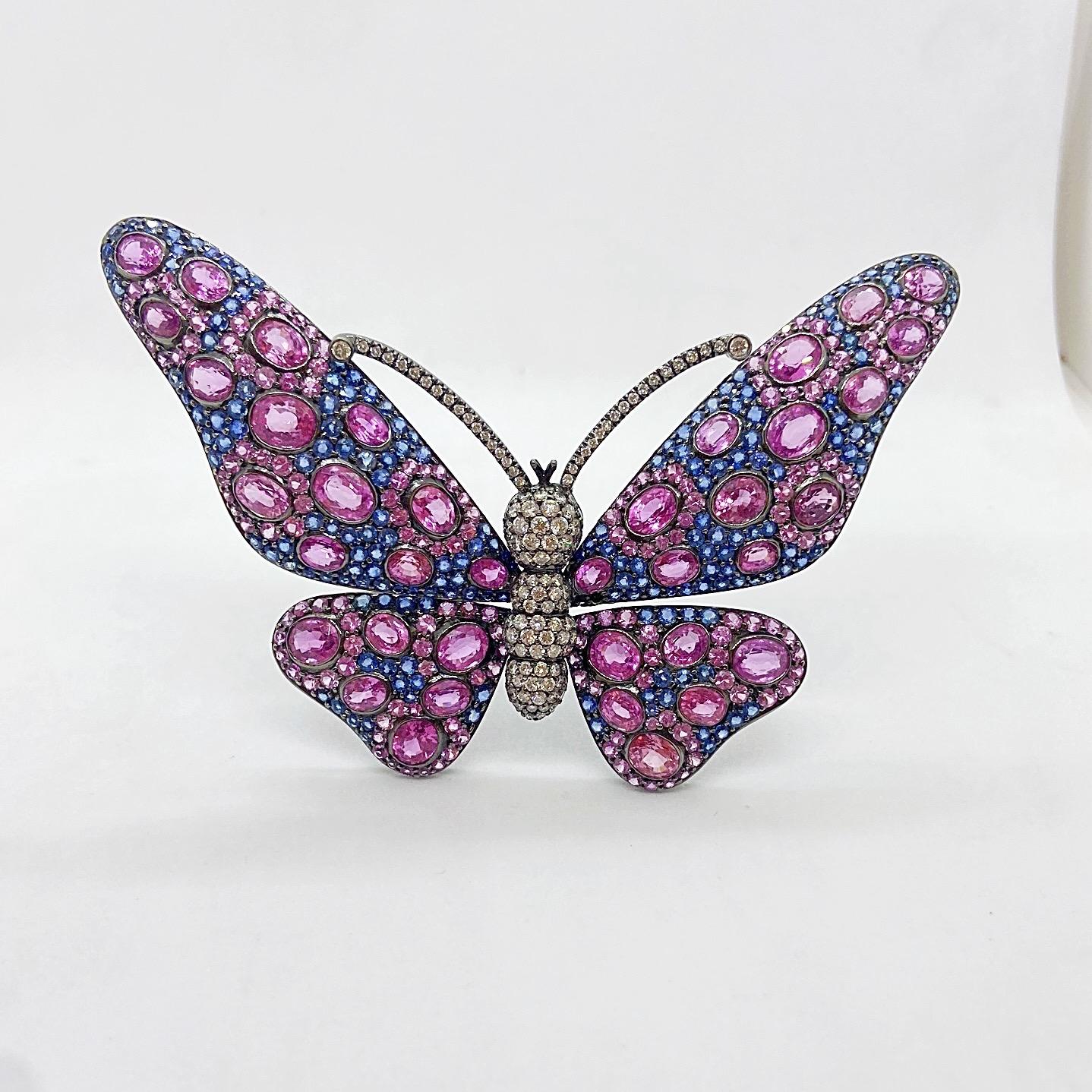 This showstopping butterfly brooch is a true statement piece. Set in 18 karat blackened gold, oval Pink Sapphires are set against a back round of round Blue Sapphires. White round Brilliant diamonds are set for the body and antennae.
The brooch