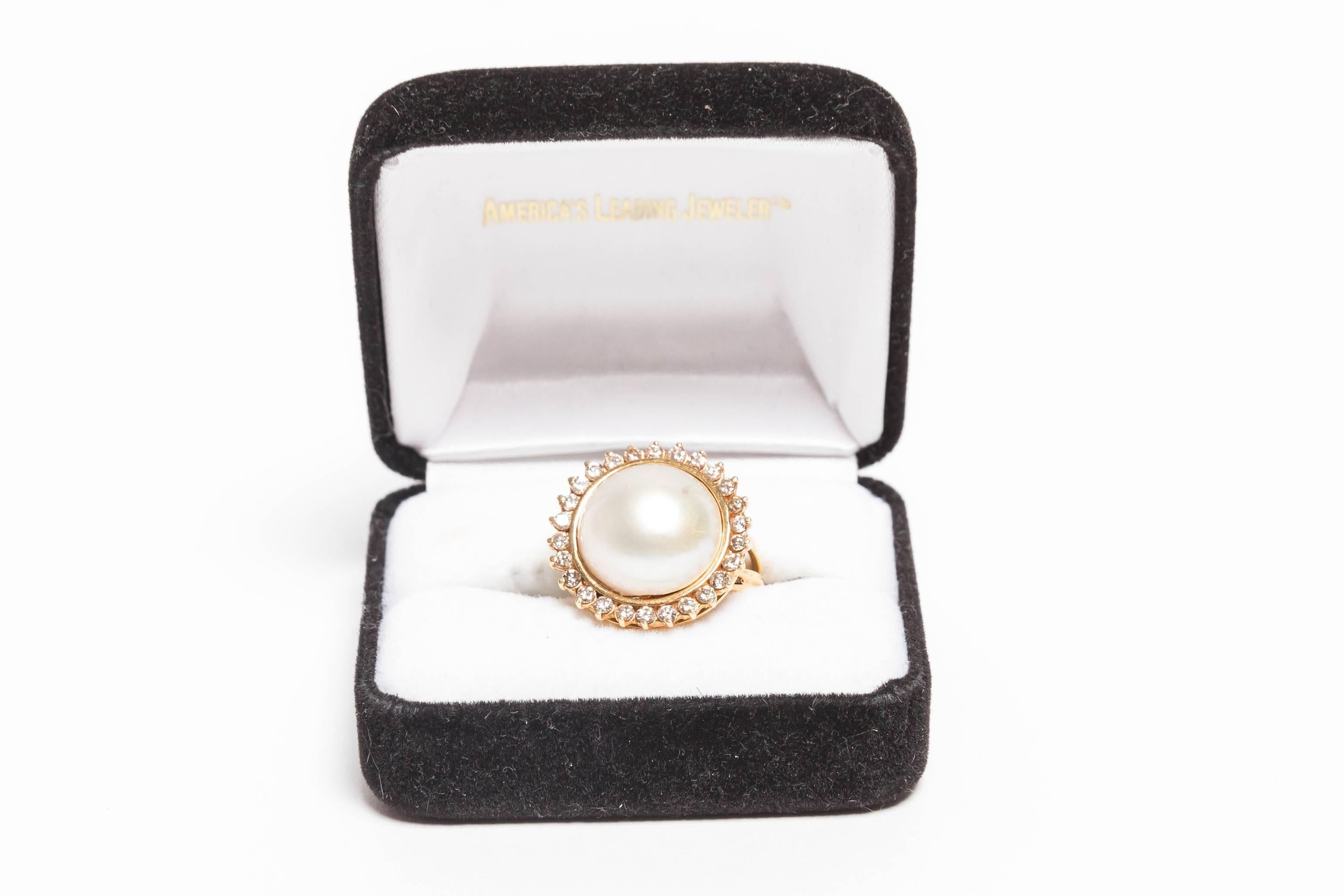 Very pretty Mabe Pearl and Diamond Cocktail Ring in 18 Kt Gold
26 round diamonds surround a gold bezel set mabe pearl
The pearl measures approximately 5/8ths of an inch
Ring size is a 9