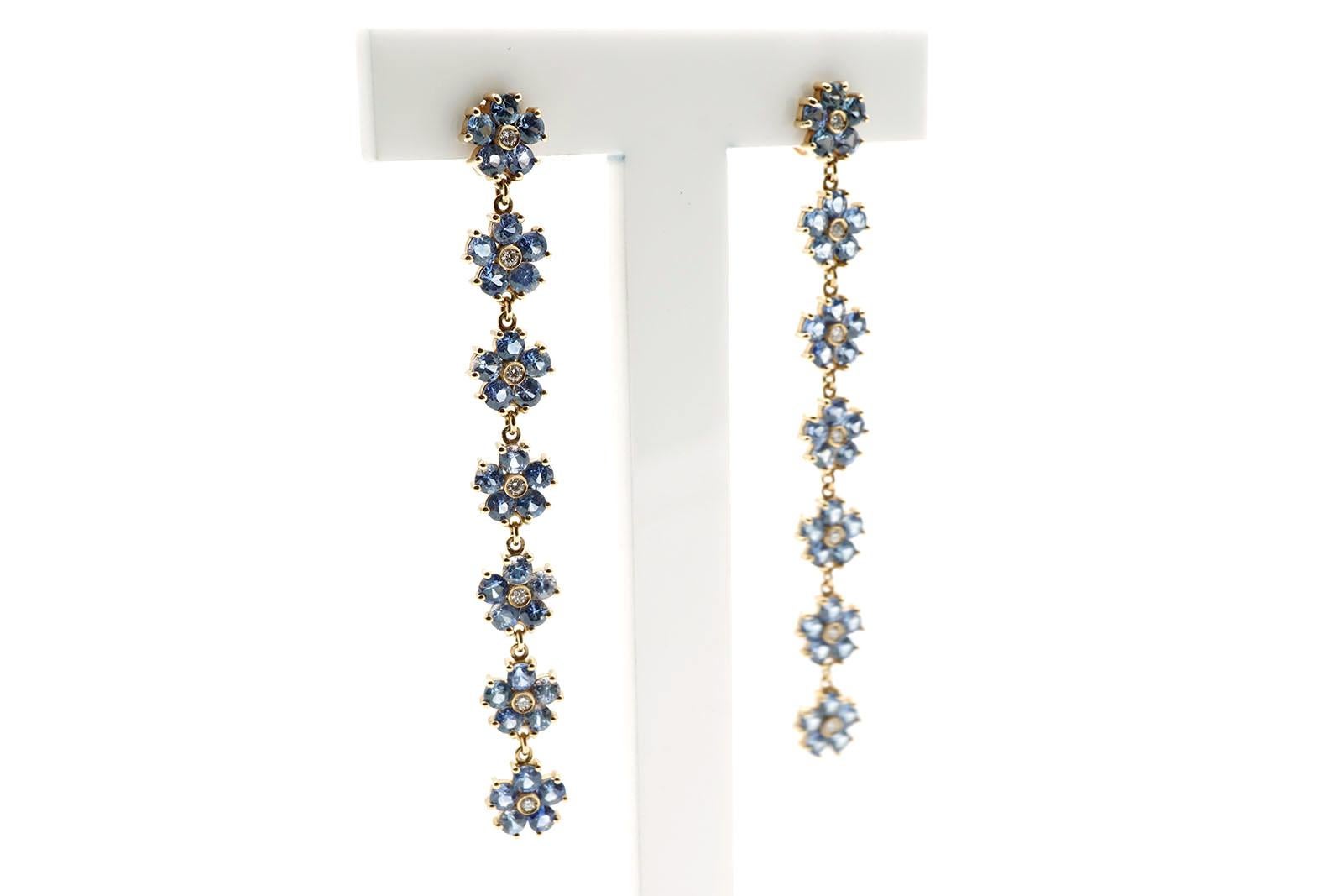 Dangle earrings made in 18 Kt gold ( gr 6,30 in total ) Sapphires ( ct 4,41 ) and Diamonds ( ct 0,14 ).
Each earring is composed by seven flowers. 
Each flower has five blue sapphires and a diamond in the centre.
The length of these earrings is cm