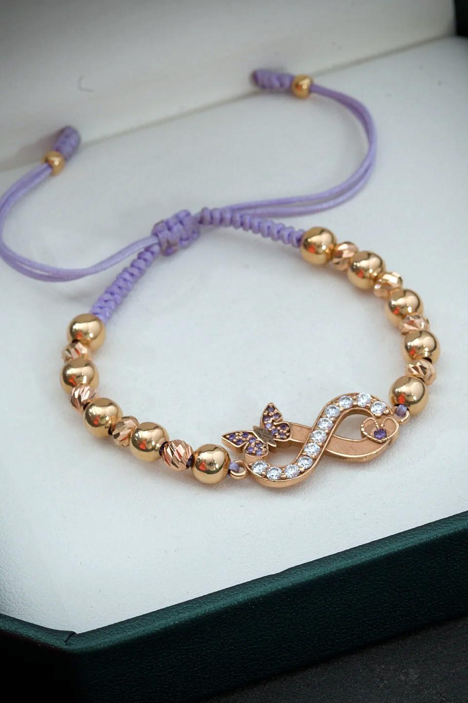 18 karat rose gold bracelet with a central infinity sign encrusted with 0.38 carats of moissanite, 10 smooth balls and 10 faceted balls in various sizes, mounted on adjustable purple thread

Total weight of the bracelet: 4.95 grams
Weight of the
