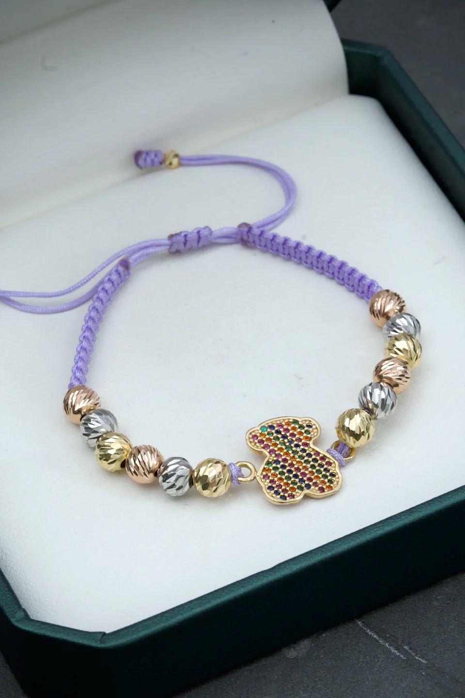 Bracciale in oro 18 carati con un grande orso incrostato di cristalli multicolori e 14 sfere sfaccettate in oro giallo, bianco e rosa, montato su filo viola regolabile

Peso totale del bracciale: 4,65 grammi
Peso dell'orso: 1,8 grammi
Peso delle 14