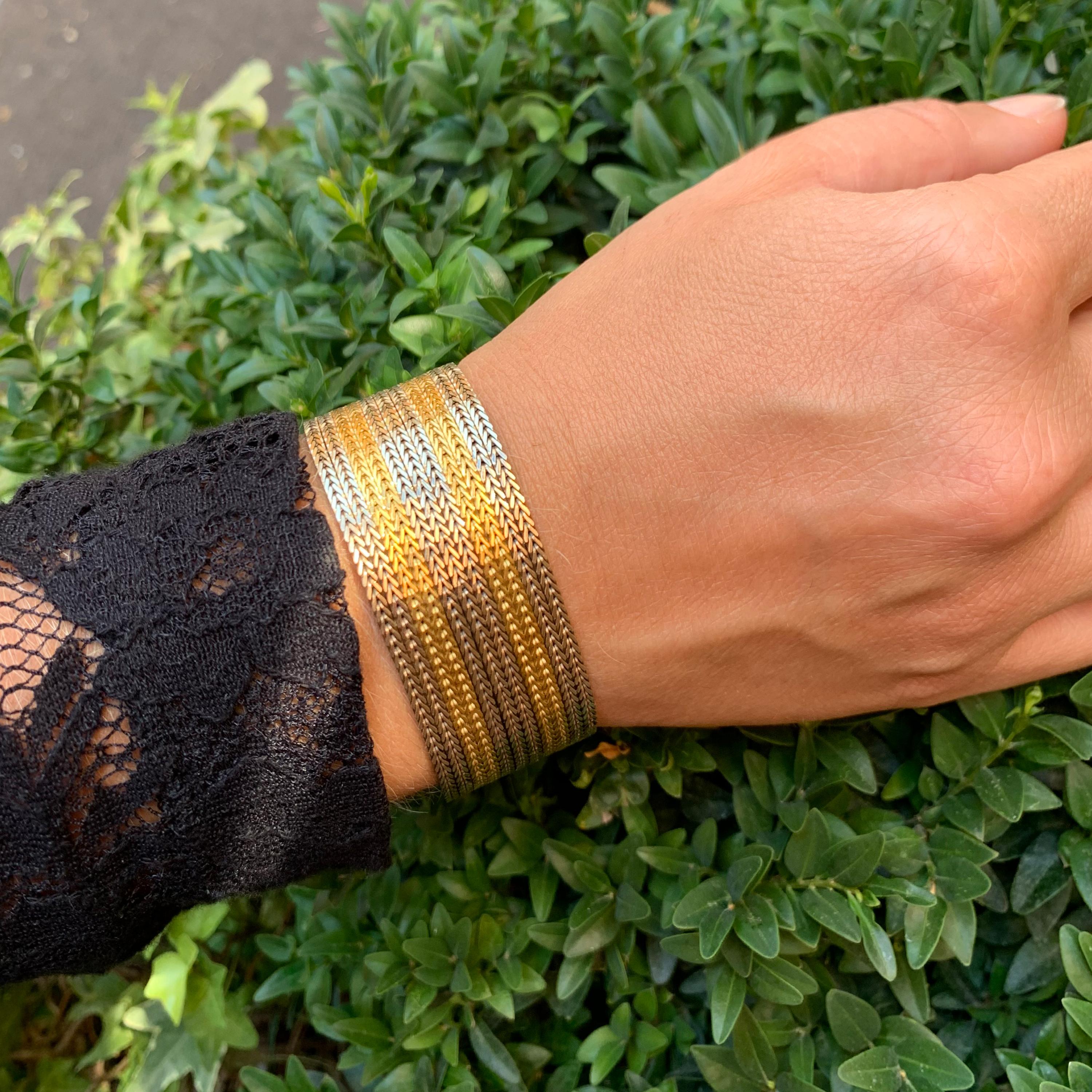 Charmant et lourd bracelet au traitement complexe réalisé en alternant des bandes entrelacées d'or blanc et jaune pour former un doux tissu doré. Le bracelet est agrémenté d'une fermeture linéaire faite à la main. L'utilisation de deux couleurs d'or