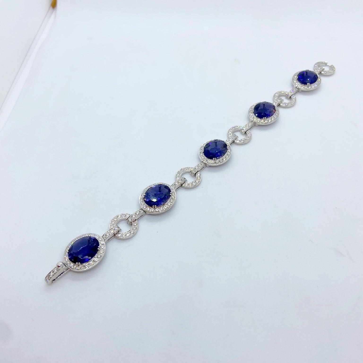 18 karat white gold bracelet set with 5 oval Iolite stones. Each oval stone is set in a bezel of round brilliant Diamonds.. Alternating between the Iolites are round links with the same Diamond setting. The clasp is also set with Diamonds for a