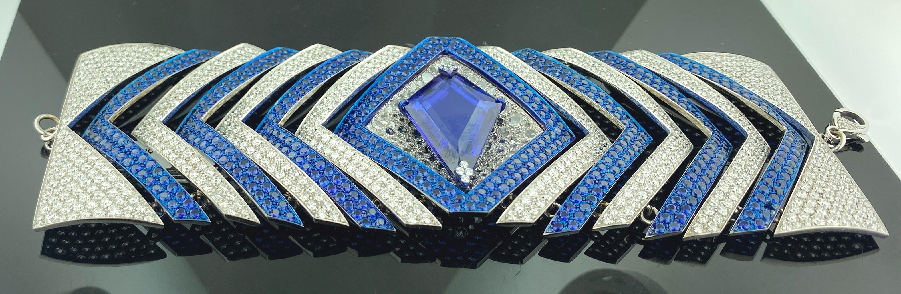 Set in 18 karat white gold and Titanium is a 17.74 carat Tanzanite center stone plus another 17.28 carats of round cut blue sapphires and 23.50 carats of round brilliant cut diamonds. 45.69 grams of gold and 5 grams of Titanium.