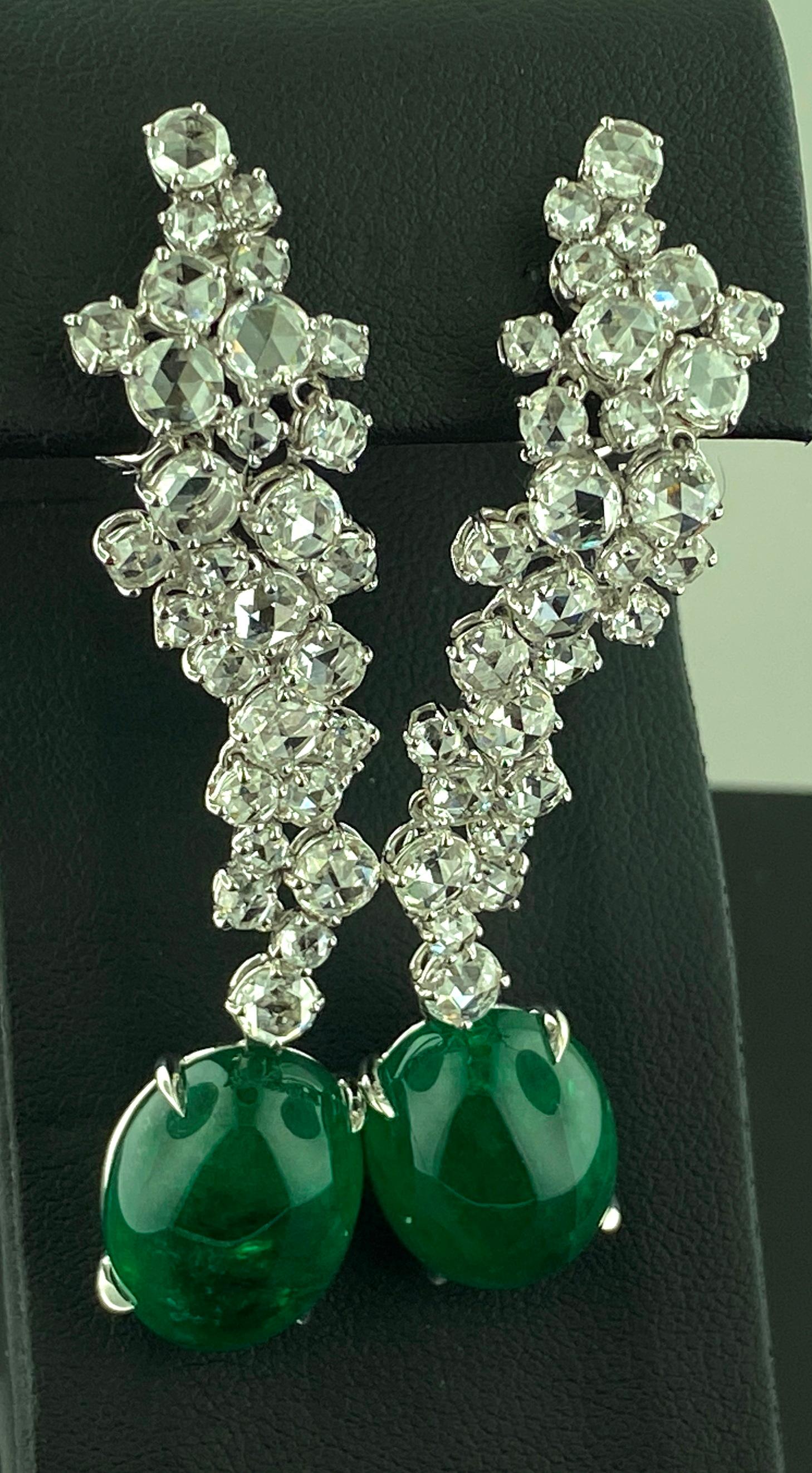 set in 18 karat white gold 6.90 carats, total diamond weight for both ears, of round brilliant cut diamonds with 2 oval cut Cabochon Emeralds at the bottom with a total weight of 26.07 carats.