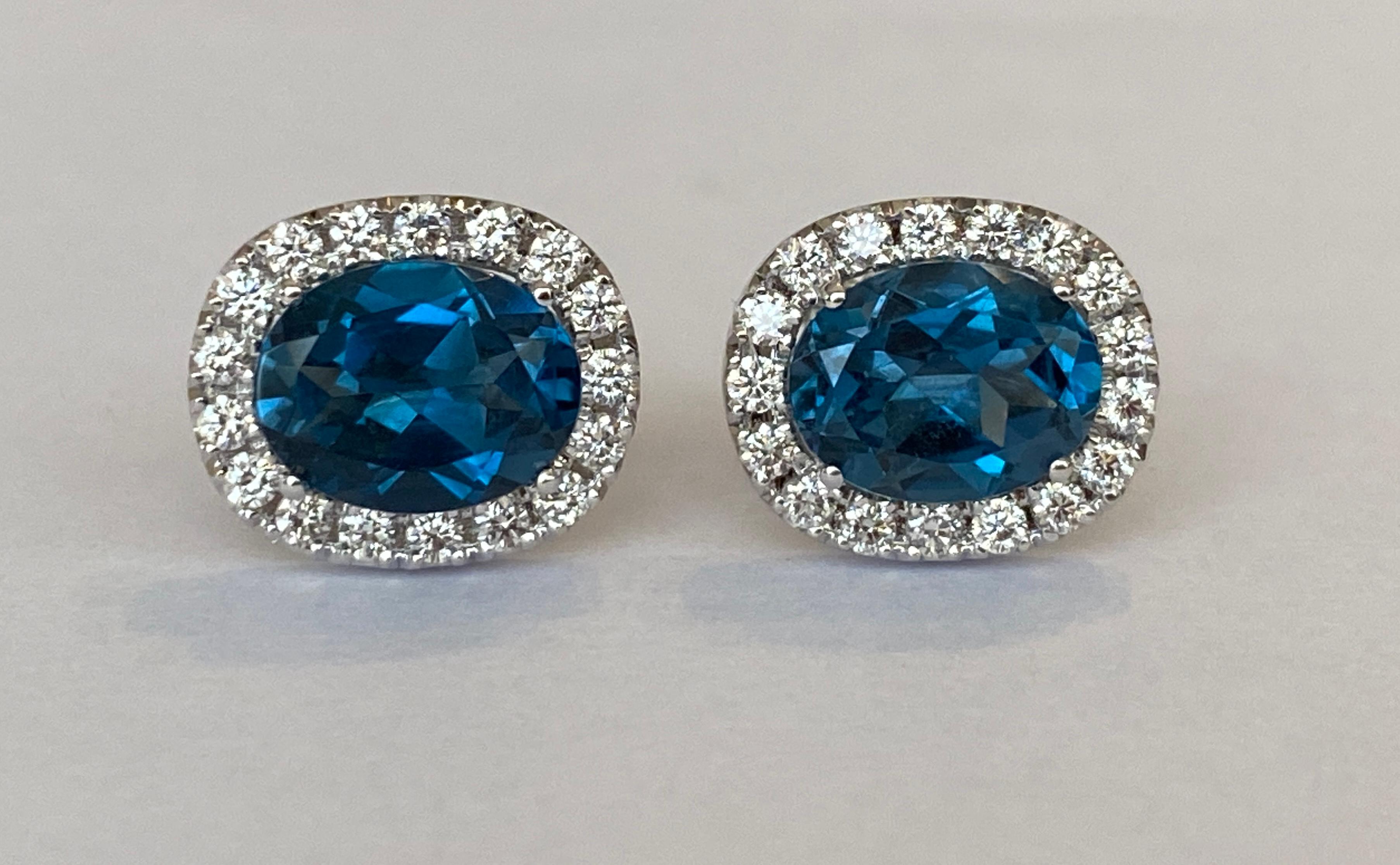 Offered in new condition, stud earrings in white gold, with two pieces of oval cut London Blue Topaz of approx. 4.5 carats together. The stones are surrounded by an entourage of 32 brilliant cut diamonds totaling approx. 0.58 ct of quality