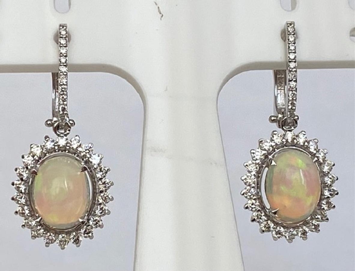 Offered in new condition, magnificent ear studs made of white gold, with two cabochon oval cut opals of 4,150 carat combined. The stones are surrounded by an entourage of 64 brilliant cut diamonds of approx. 1.25 ct in total of G/VS/SI quality. One