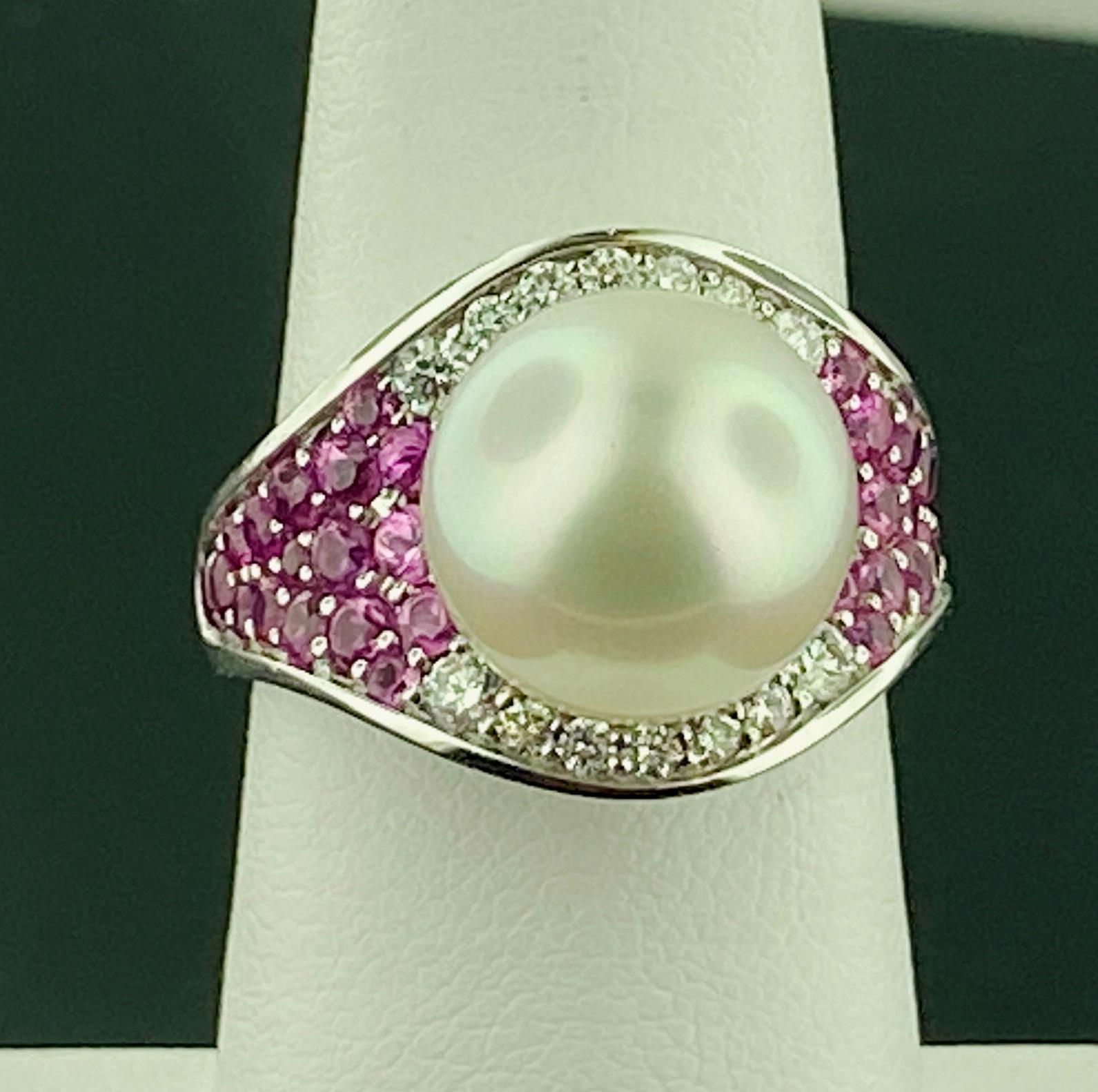 Set in 18 karat white gold, weighing 13.68 grams, is one white South Sea Pearl, measuring 11.85 millimeters, with 34 Round Brilliant Cut Pink Sapphires weighing 1.35 carats and 14 Round Brilliant Cut diamonds weighing 0.25 carats, Color Grade of: