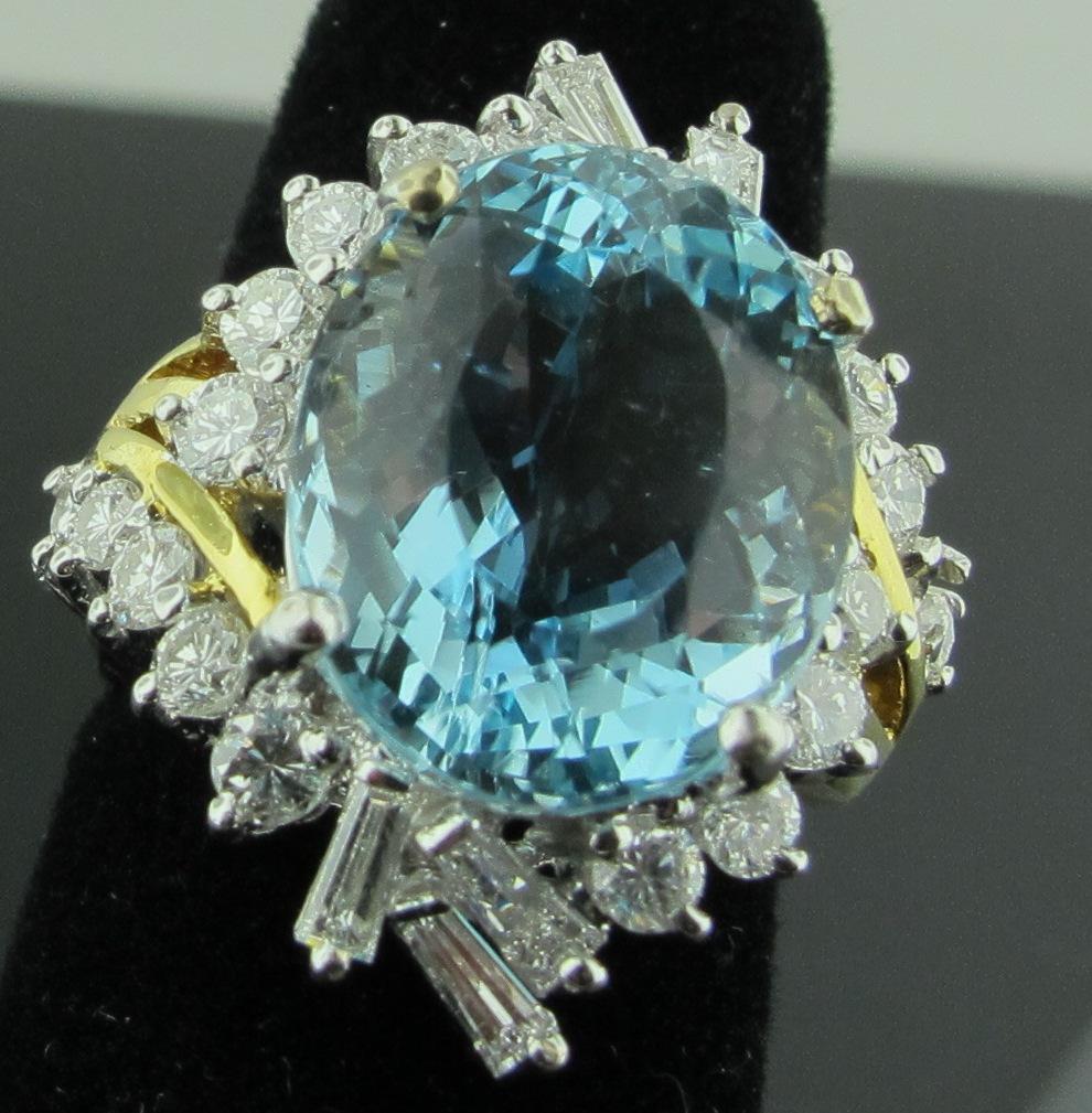 Set in 18 karat yellow gold, a 9 carat Oval shaped Aquamarine, surrounded by 24 diamonds, 6 baguettes and 18 round brilliant cut stones, with a total weight of approximately 1.55 carats.  Ring Size 5 3/4