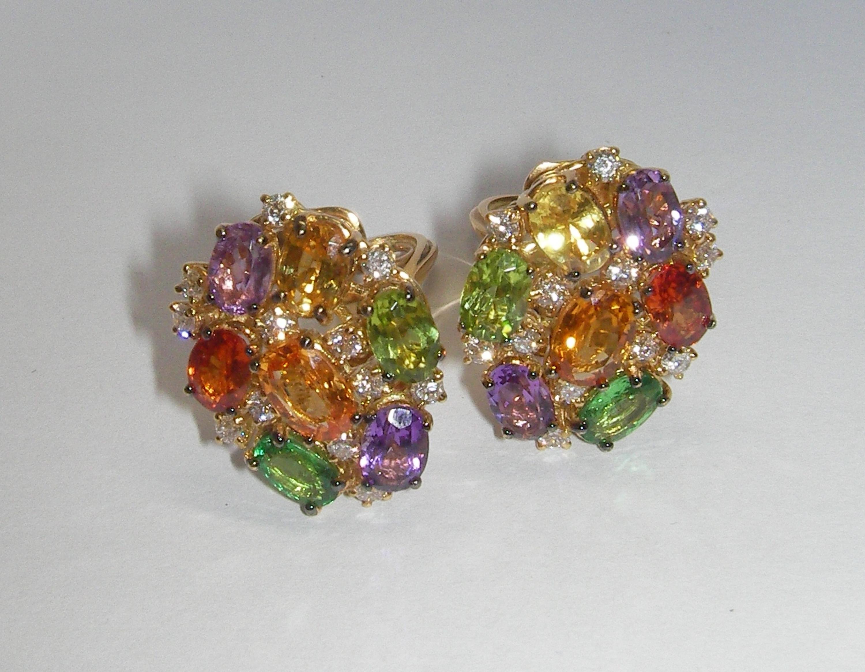 These 18 Karat Yellow Gold Cluster Earrings are truly magnificent. Diamonds accenting the beautiful array of colorful Peridot, Amethyst, Green Garnet, Yellow Sapphire and both Orange and Dark Orange Sapphire. A perfect compliment to our 18 Karat