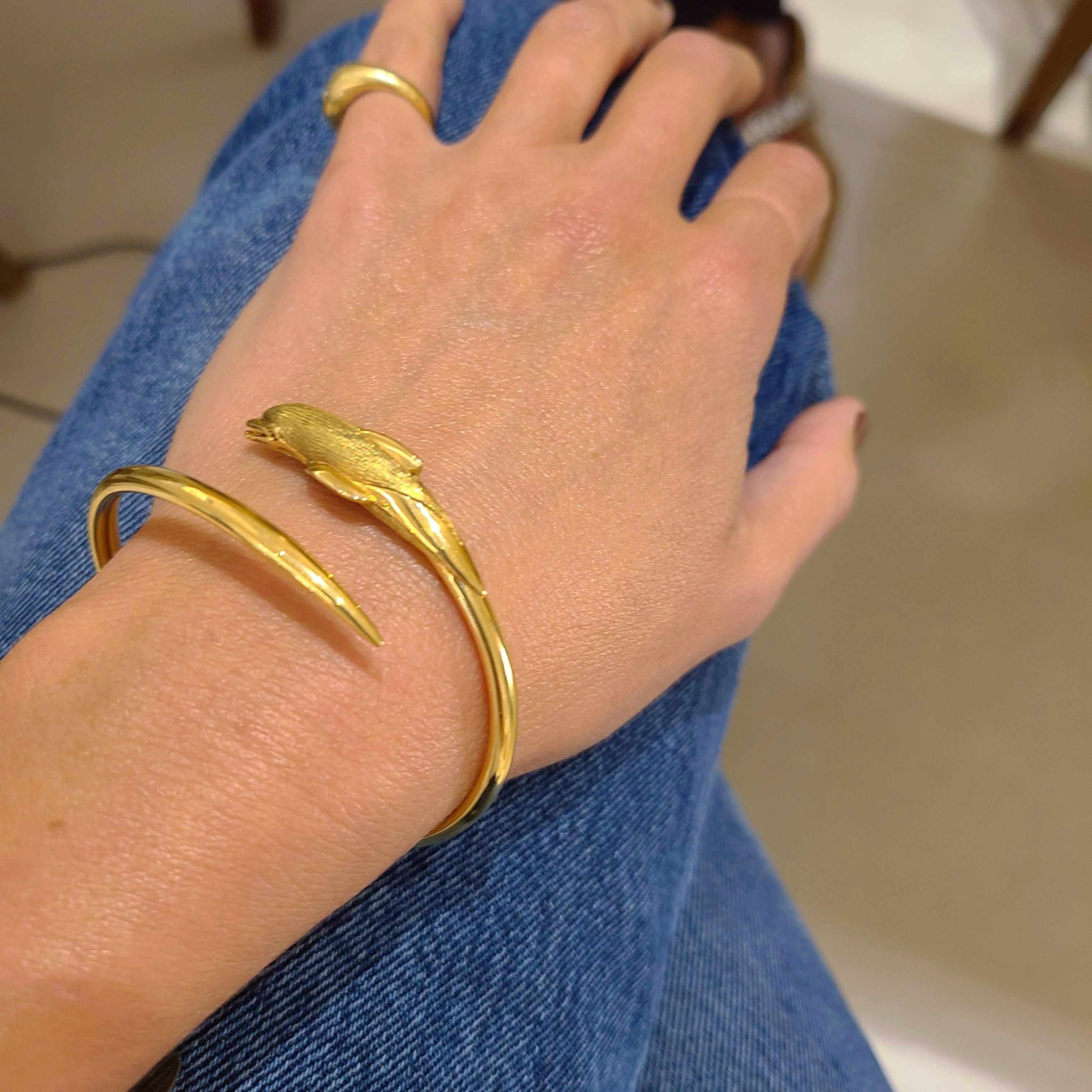 Easy to wear 18 karat yellow gold bracelet, at Cellini Jewelers NYC is Designed as a dolphin in a hi-polish and sandblasted finish. The eyes are set with brilliant cut rubies. 
The bracelet measures 2.50