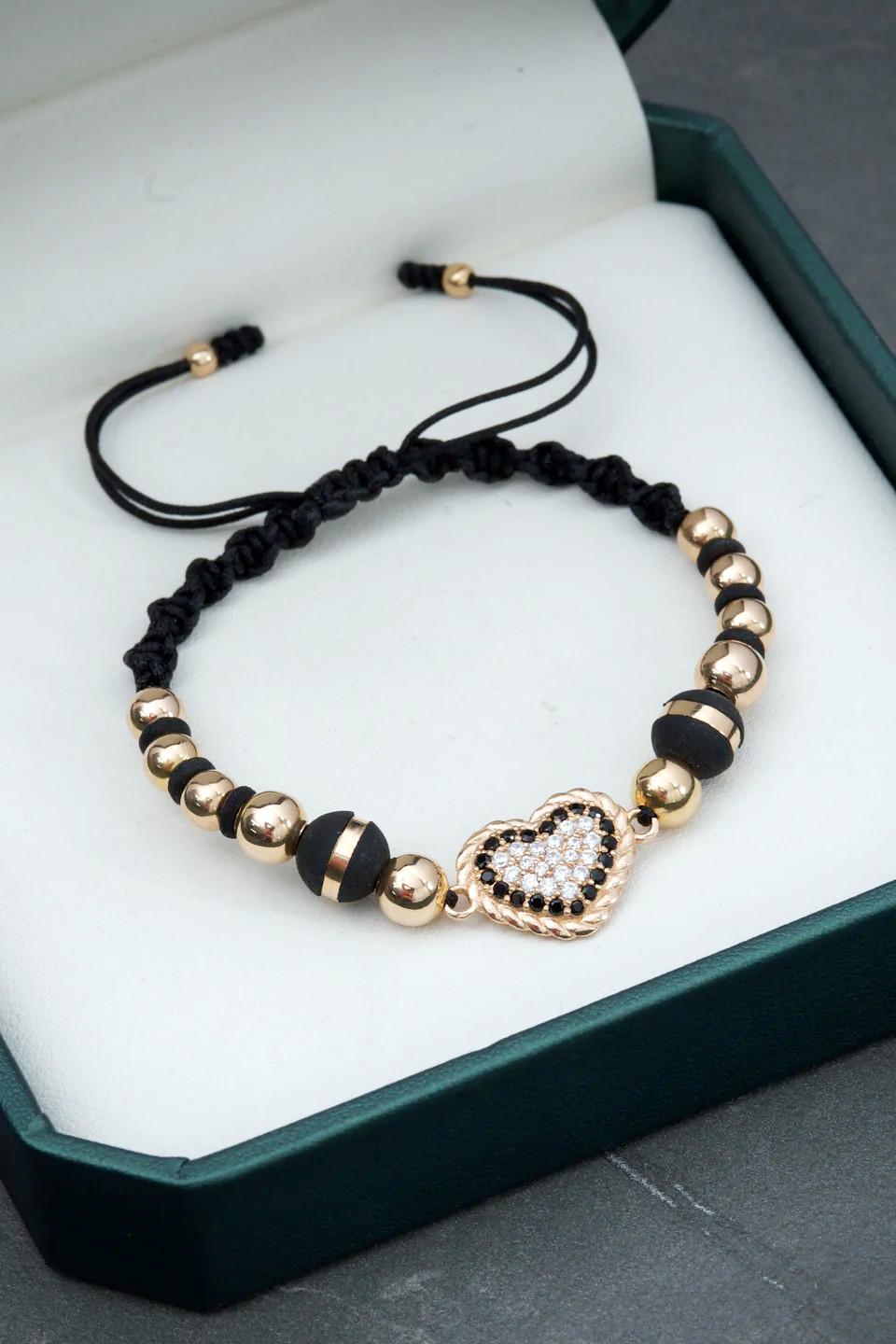 Bracciale in oro giallo 18 carati con un cuore centrale incrostato di cristalli Swarovski chiari e neri, 2 palline neoros e 12 palline lisce di varie dimensioni, montato su filo nero regolabile

Peso totale del bracciale: 4 grammi
Peso del cuore: