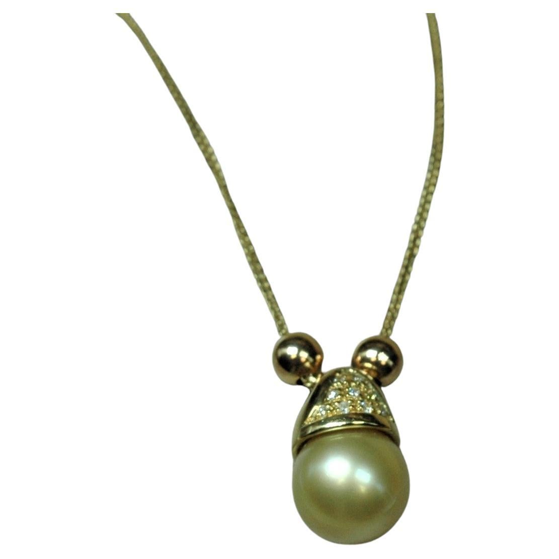 Very particular this 18 kt. yellow gold necklace with a gold pearl mounted with a rounded cotter pin and embellished with a small brilliants pave. The pendant slides smoothly on the chain accompanied laterally by two small spheres in yellow gold.