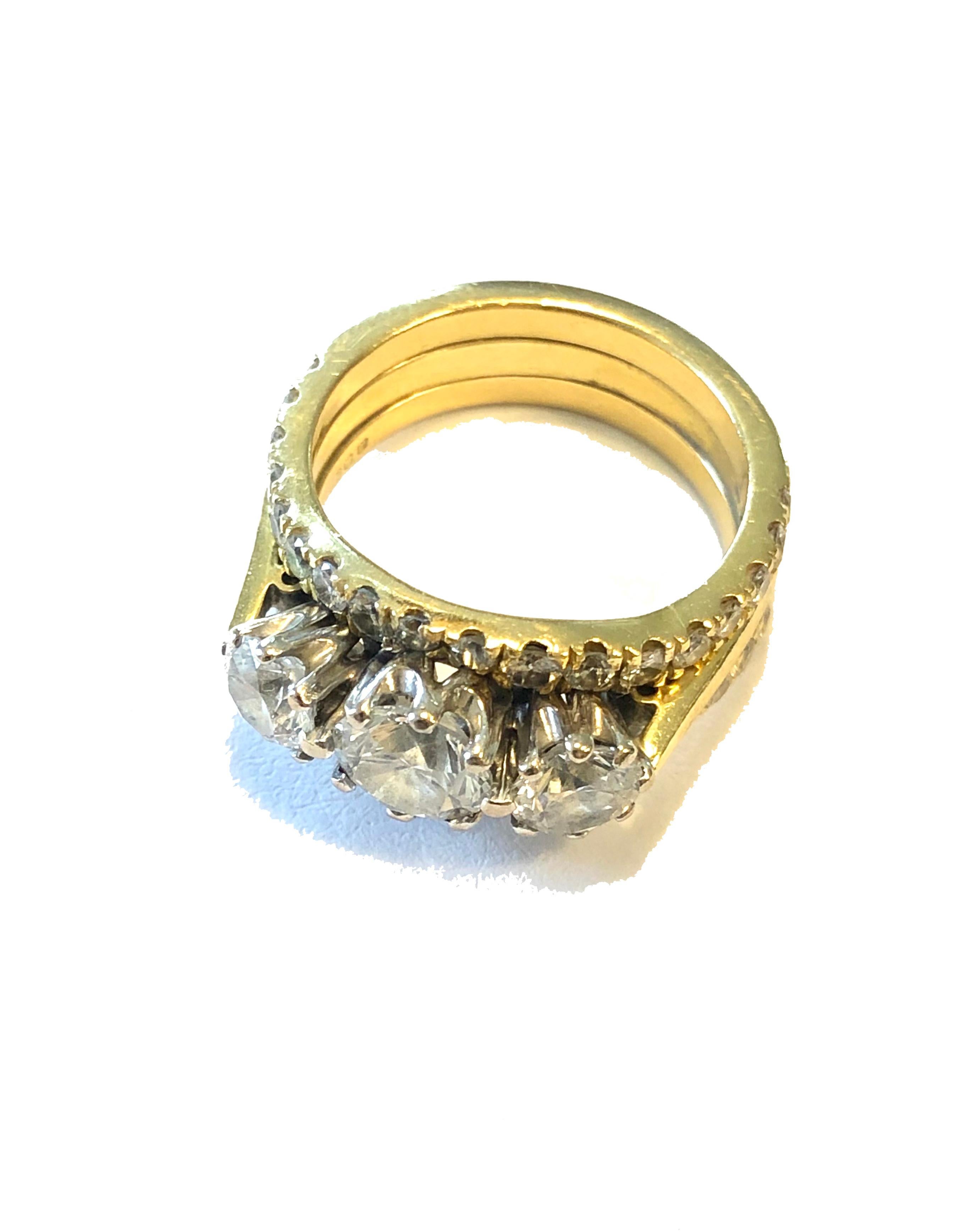 An 18 Kt yellow and white gold 2.16 Ct diamond cluster ring. The three stone diamond central ring in yellow gold, the diamonds set in white gold, the central brilliant cut diamond 0.75 Ct with two round brilliant cut diamonds of 0.4 Ct and 0.41 Ct