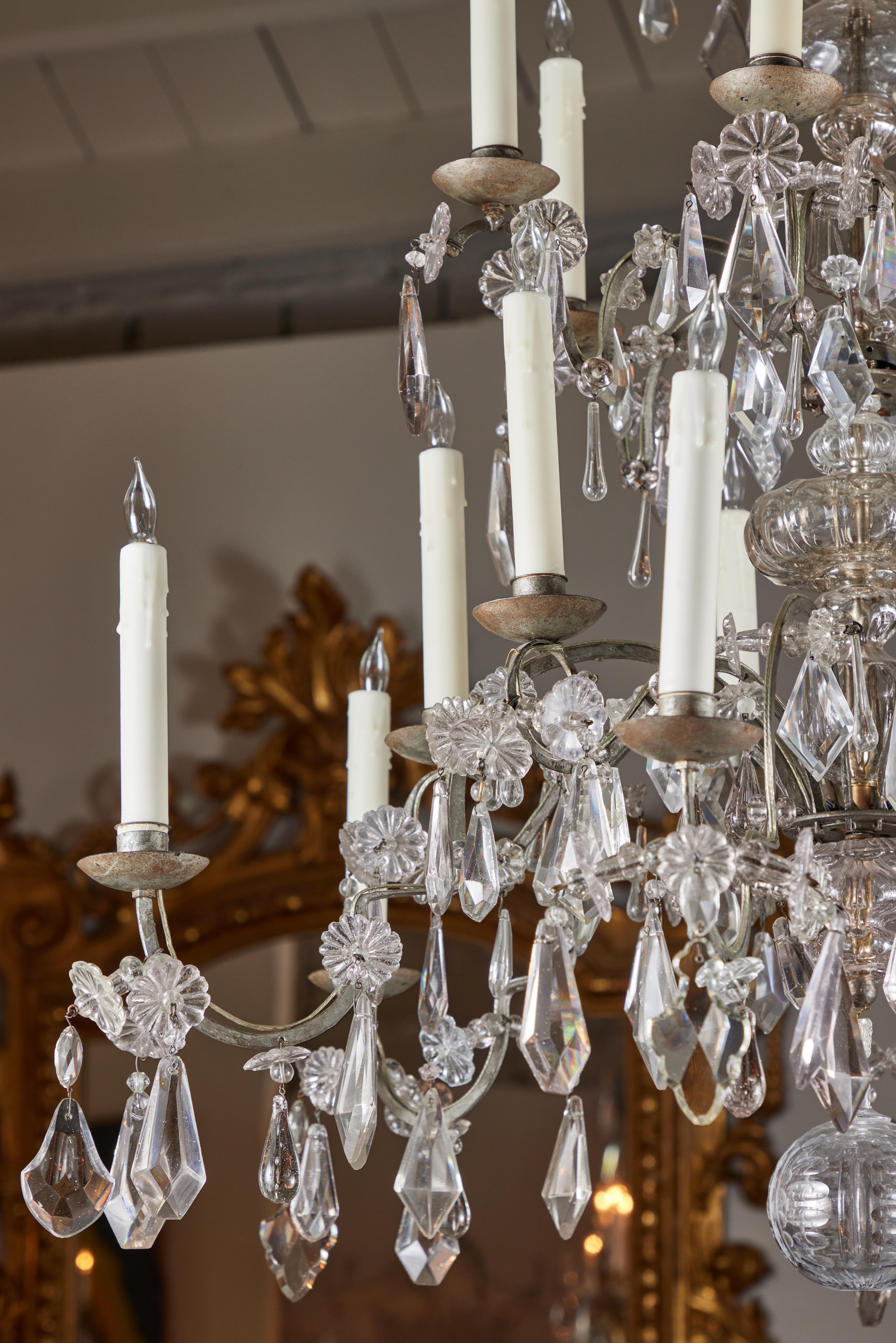 A c. 1880, silvered iron carriage chandelier with three tiers of lighting. The whole with serpentine arms amidst faceted crystal drops. The central, crystal embellished column rising to an overhanging canopy of diamond and oval drops.