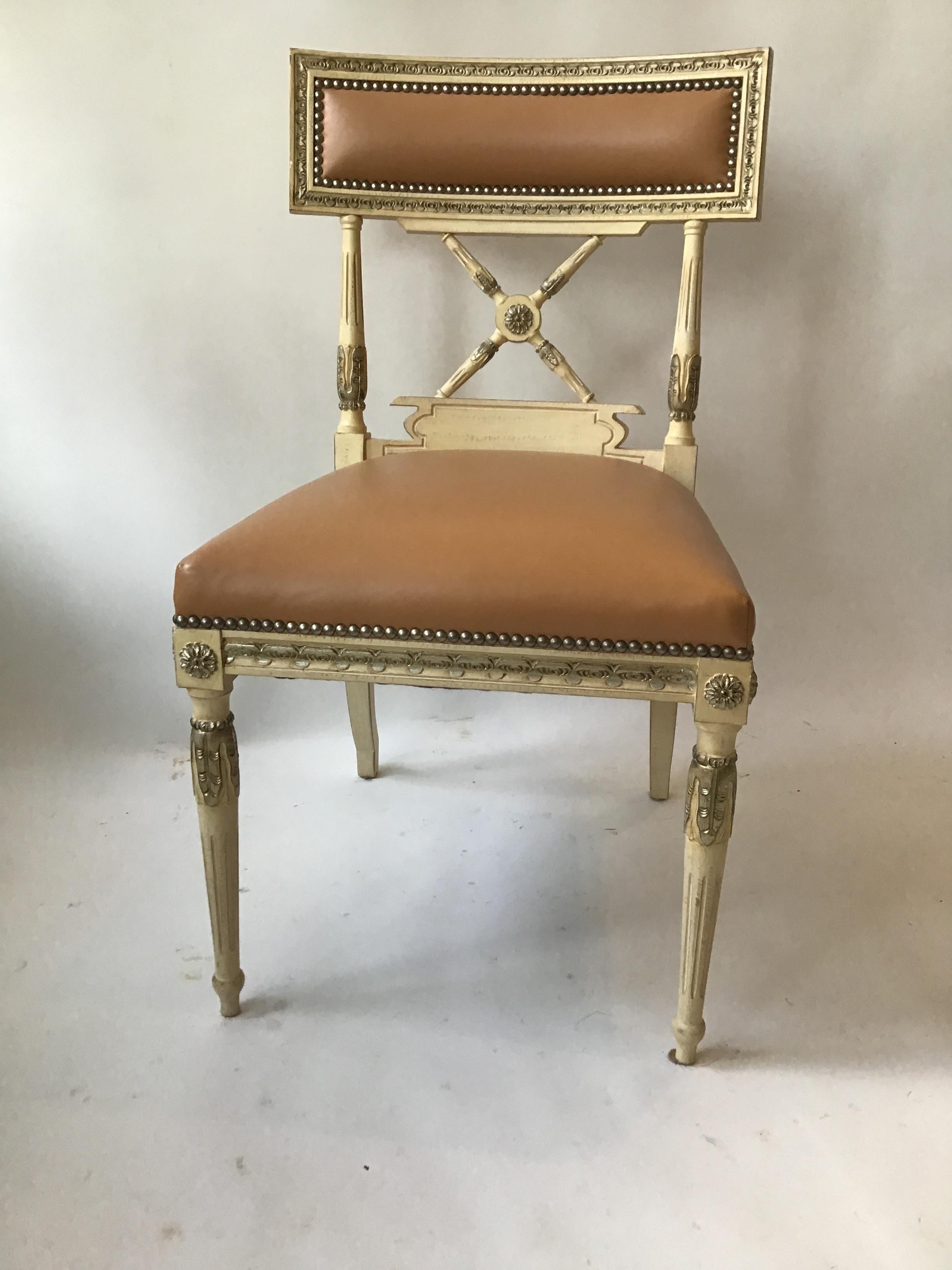 From a celebrities Southampton, NY oceanfront estate. Original cost was 3500.00 per chair. 18 Regency style carved wood dining chairs. Highlighted details in silver leaf. High quality supple faux leather.
 Price is 975.00 per chair. Sold in even
