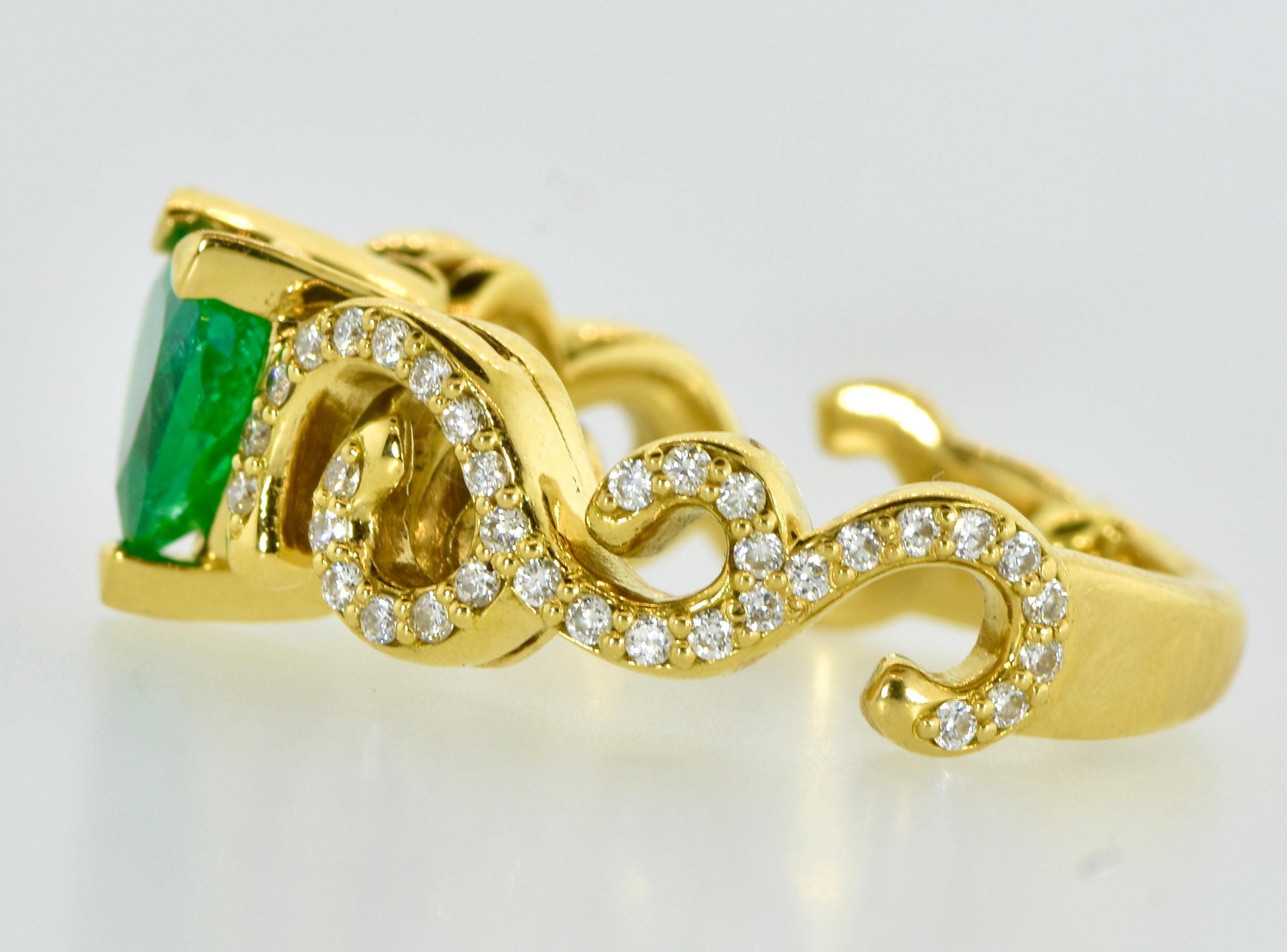 18K yellow gold centering a fine heart shaped bright green emerald with white brilliant cut diamonds in a scroll like design. The emerald is estimated to weigh 0.75 cts., and the 68 brilliant cut diamonds are estimated to weigh 0.70 cts., the