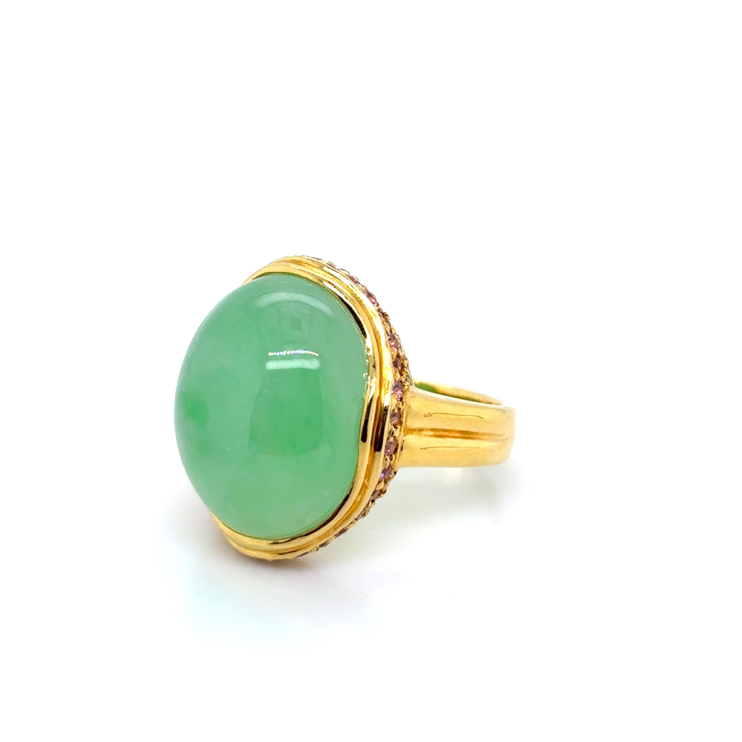 Questo squisito anello di fidanzamento è una sinfonia di colori e significati, con un centro di giada ovale liscia, affiancato da 0,54 carati di zaffiro blu intenso e 0,23 carati di diamanti scintillanti, il tutto incastonato in caldo oro giallo 18