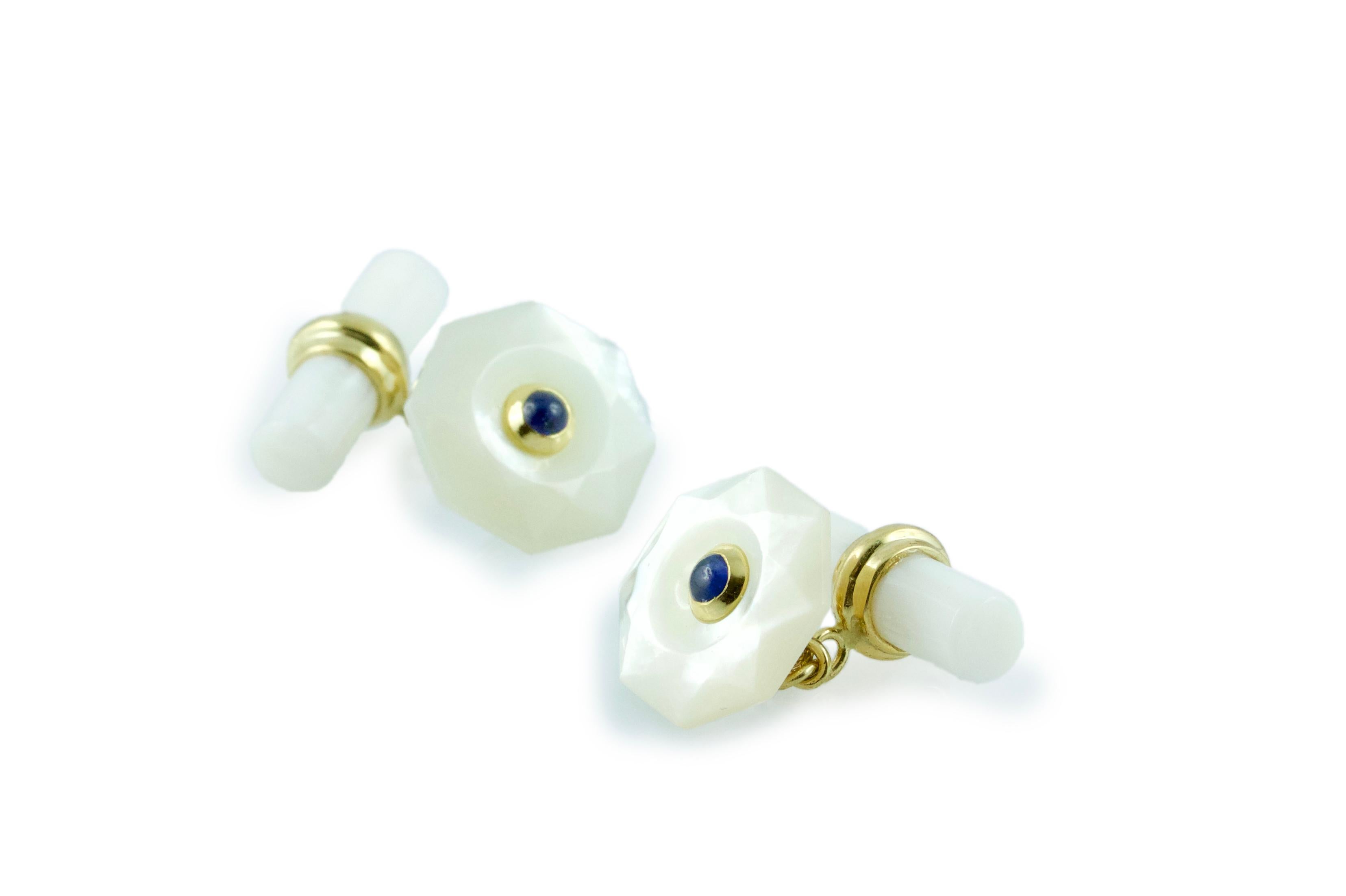 The front face of these exquisite cufflinks has a striking octagonal shape that is convex, multifaceted, and adorned in the center with a cabochon sapphire. Both the front face and the cylindrical toggle are in mother of pearl, with a post made of