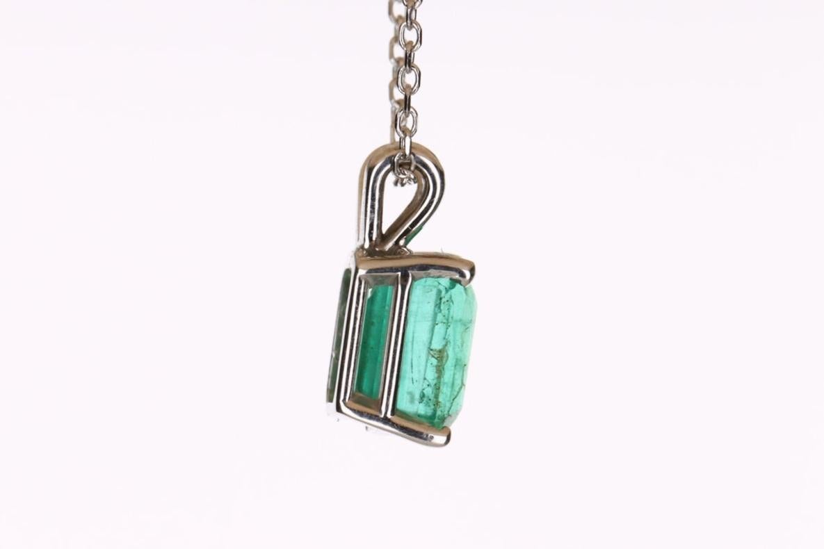 Displayed is a classic Colombian emerald solitaire necklace set in 14K white gold. This gorgeous solitaire pendant carries a full 1.80-carat emerald in a four-prong setting. Fully faceted, this gemstone showcases excellent shine. The gem has a