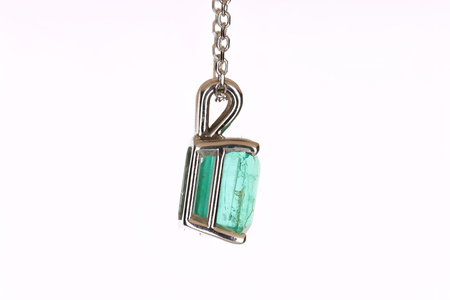 Displayed is a classic emerald solitaire necklace set in 14K white gold. This gorgeous solitaire pendant carries a full 1.80-carat earth-mined rare emerald in a four-prong setting. Fully faceted, this gemstone showcases excellent shine. The gem has