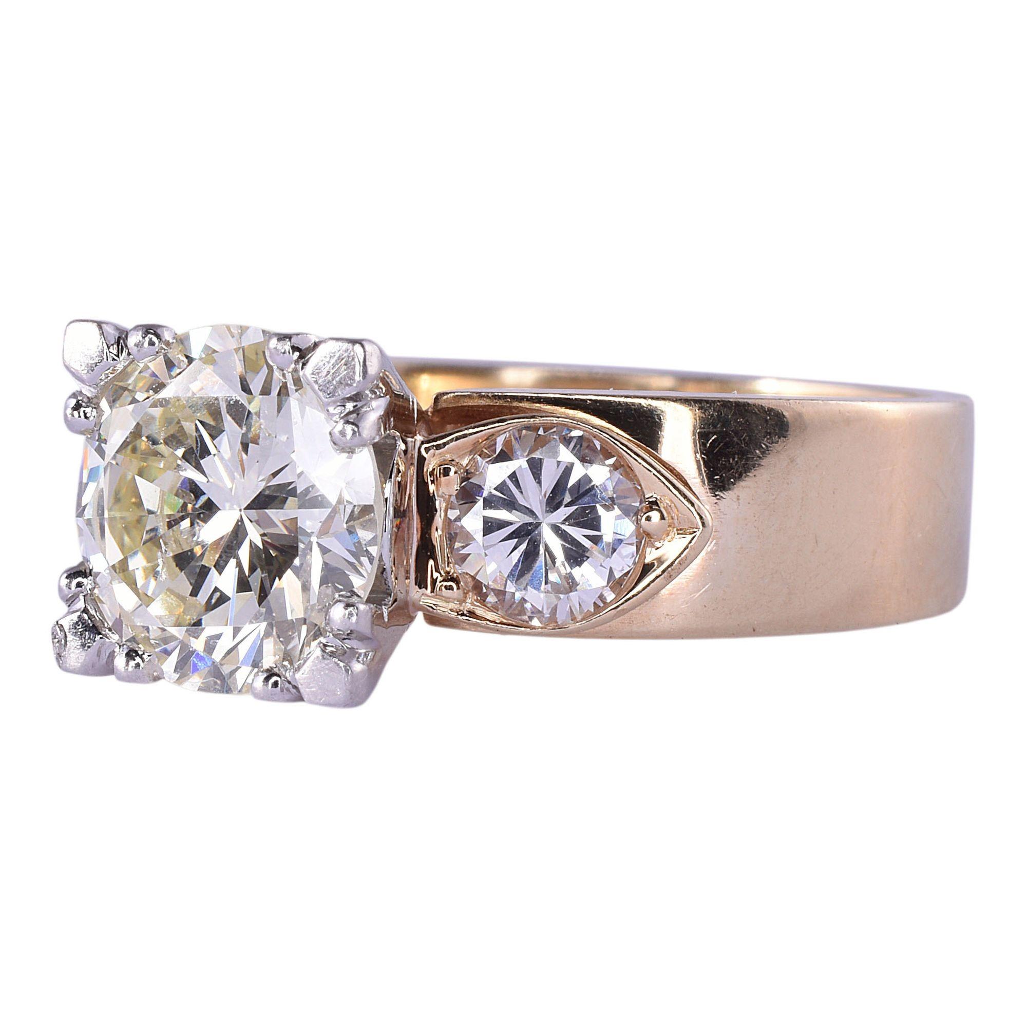 Estate 1.80 carat center diamond engagement ring. This 14 karat yellow gold wide band engagement ring features a 1.80 carat round brilliant cut center diamond with SI1 clarity and L color. There are two round brilliant cut accent diamonds at .29