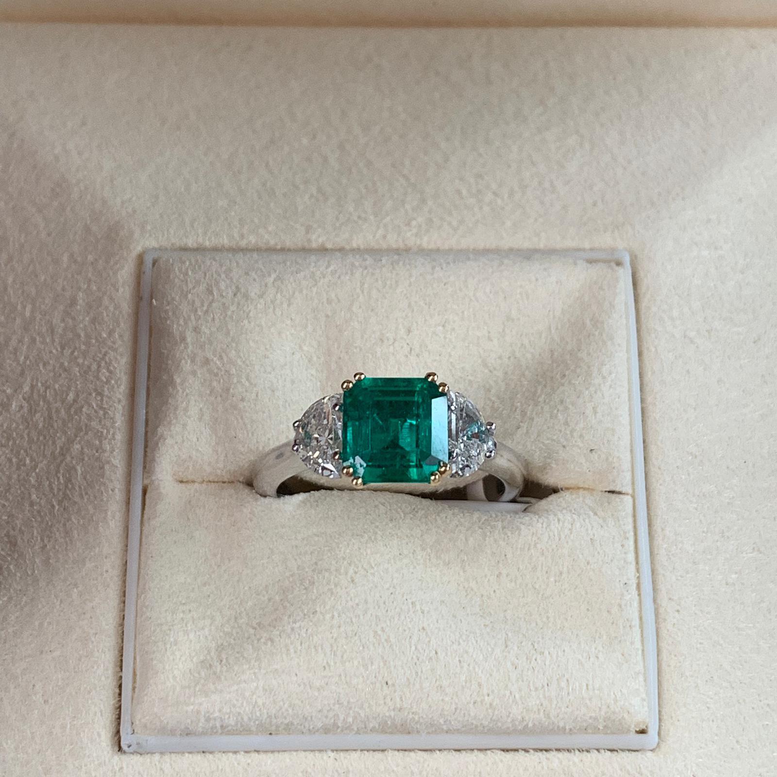 Beautiful 1.80 carats of Colombian Emerald, surrounded by 2 white trillion cut diamond 1.57 total carats. Set on 4 prong 18 karat white gold.