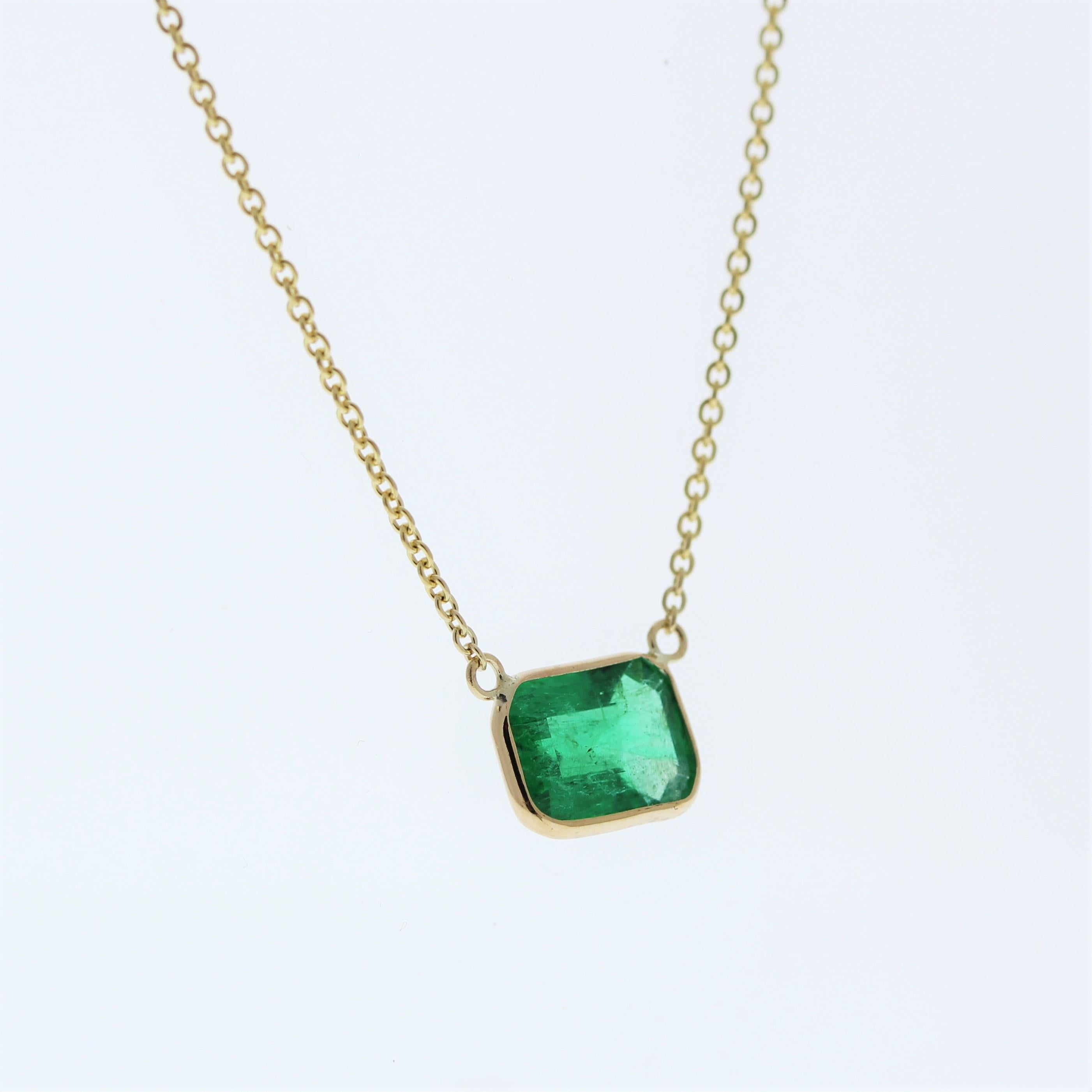 The necklace features a 1.80-carat emerald-cut emerald set in a 14 karat yellow gold pendant or setting. The emerald cut and the lush green color of the emerald against the yellow gold setting are likely to create an elegant and eye-catching fashion